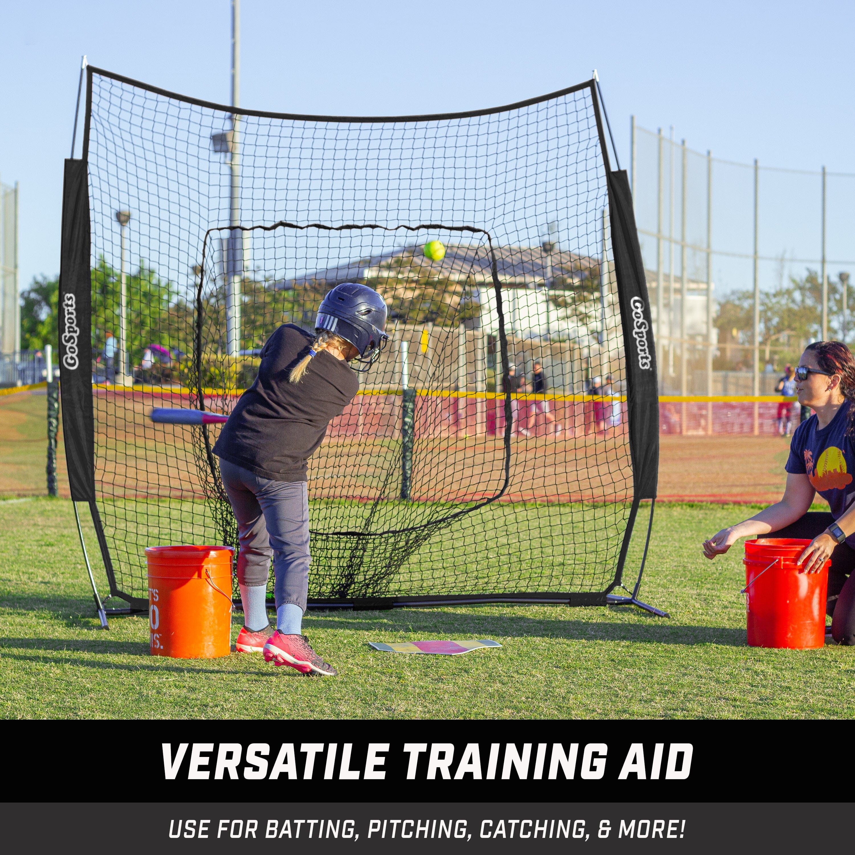 a woman is hitting a baseball ball in a net