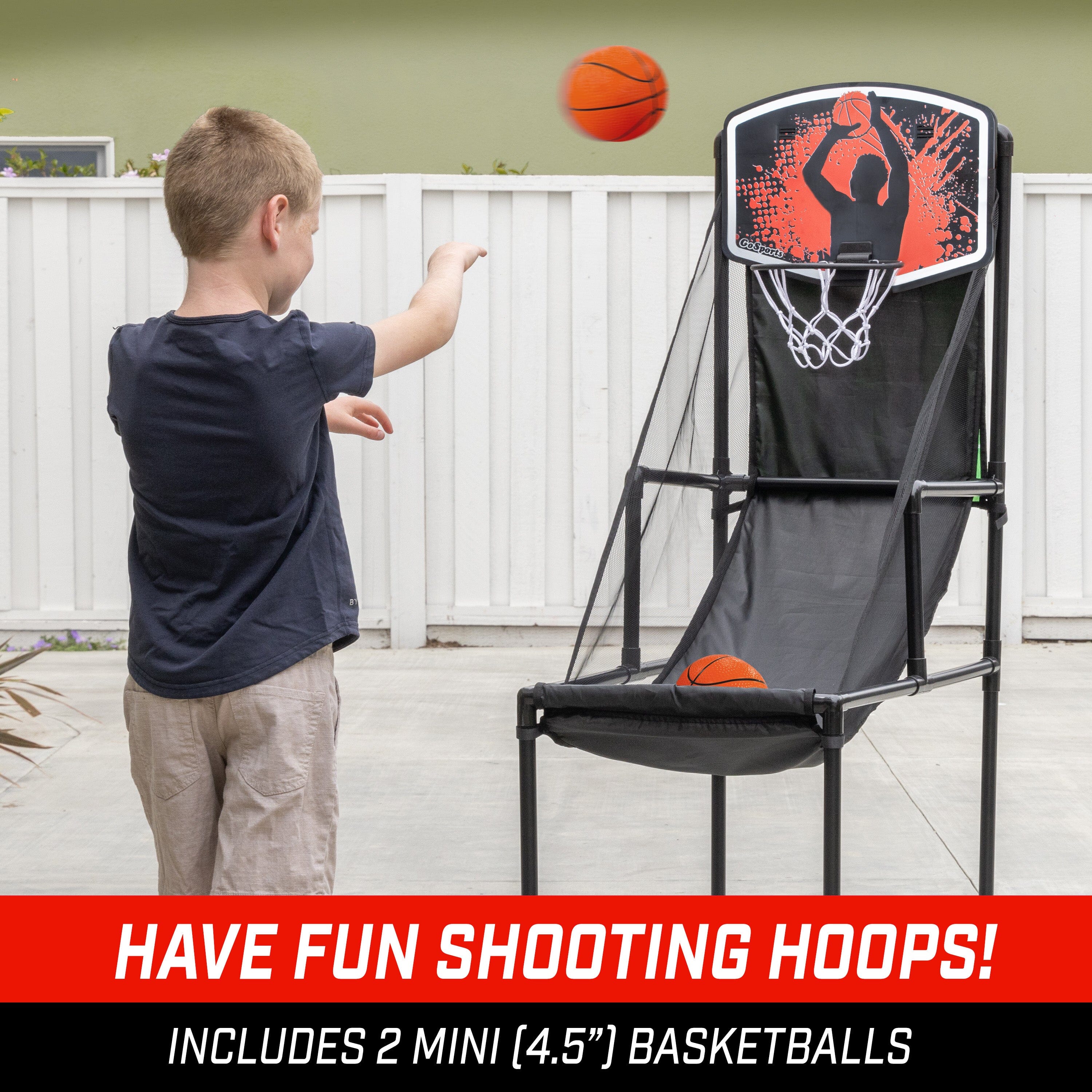 a young boy shooting basketball towards a basketball toy rim