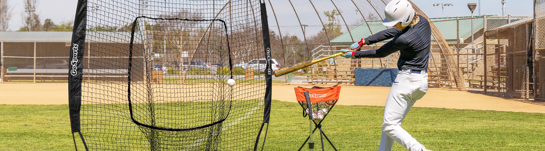 Person practicing batting in a golf practice net on a golf course