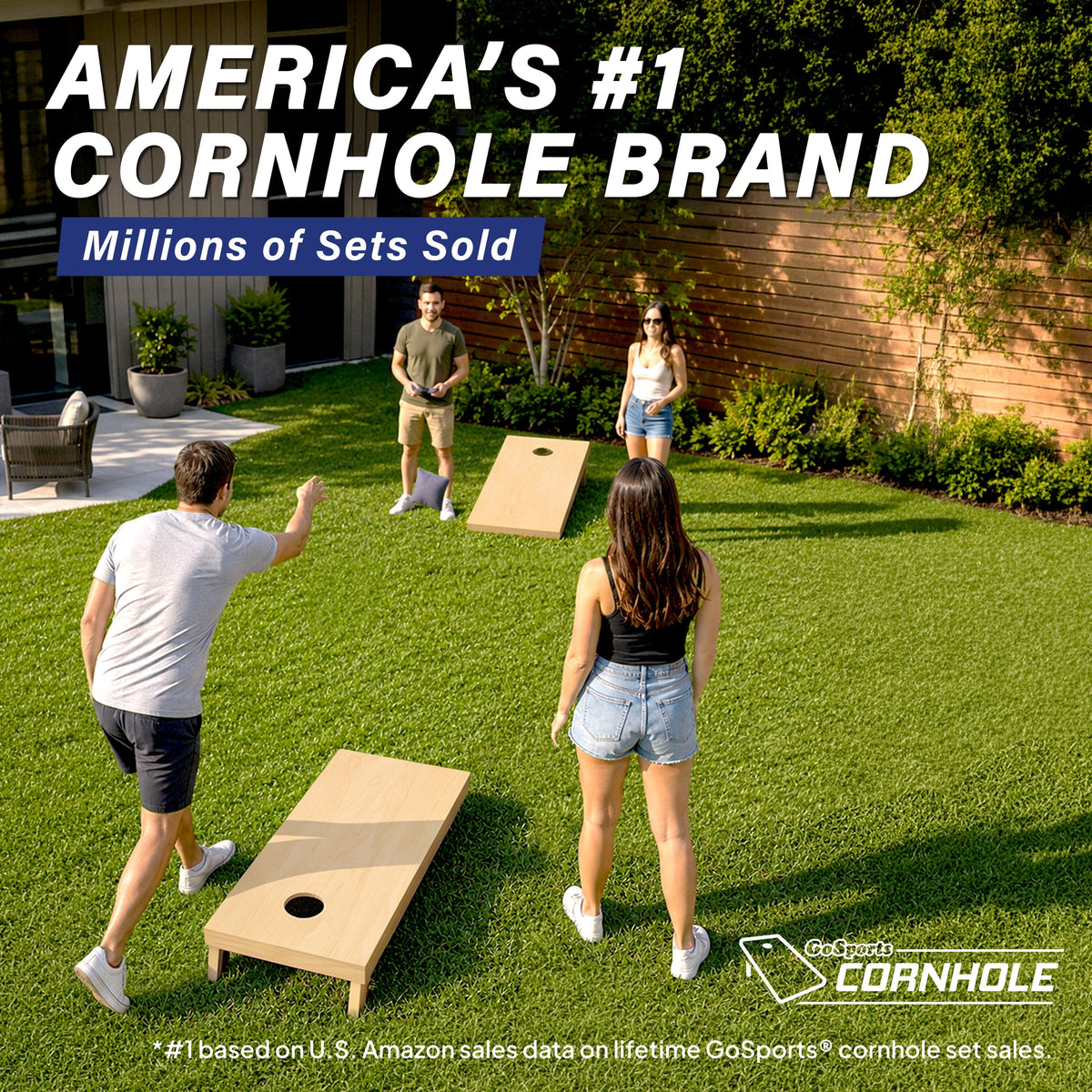 Group of friends playing on two natural wood GoSports cornhole boards set up across a sunny backyard lawn