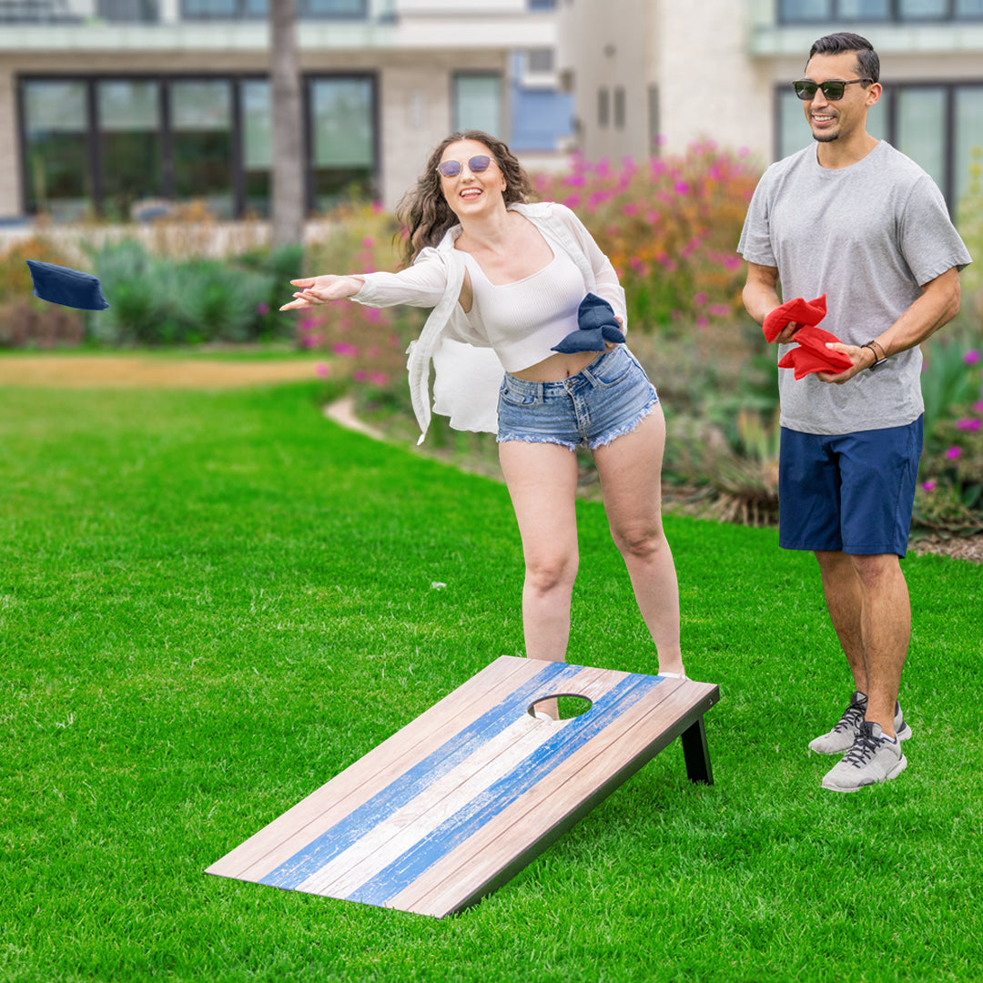 Two people playing cornhole on a grassy outdoor area.