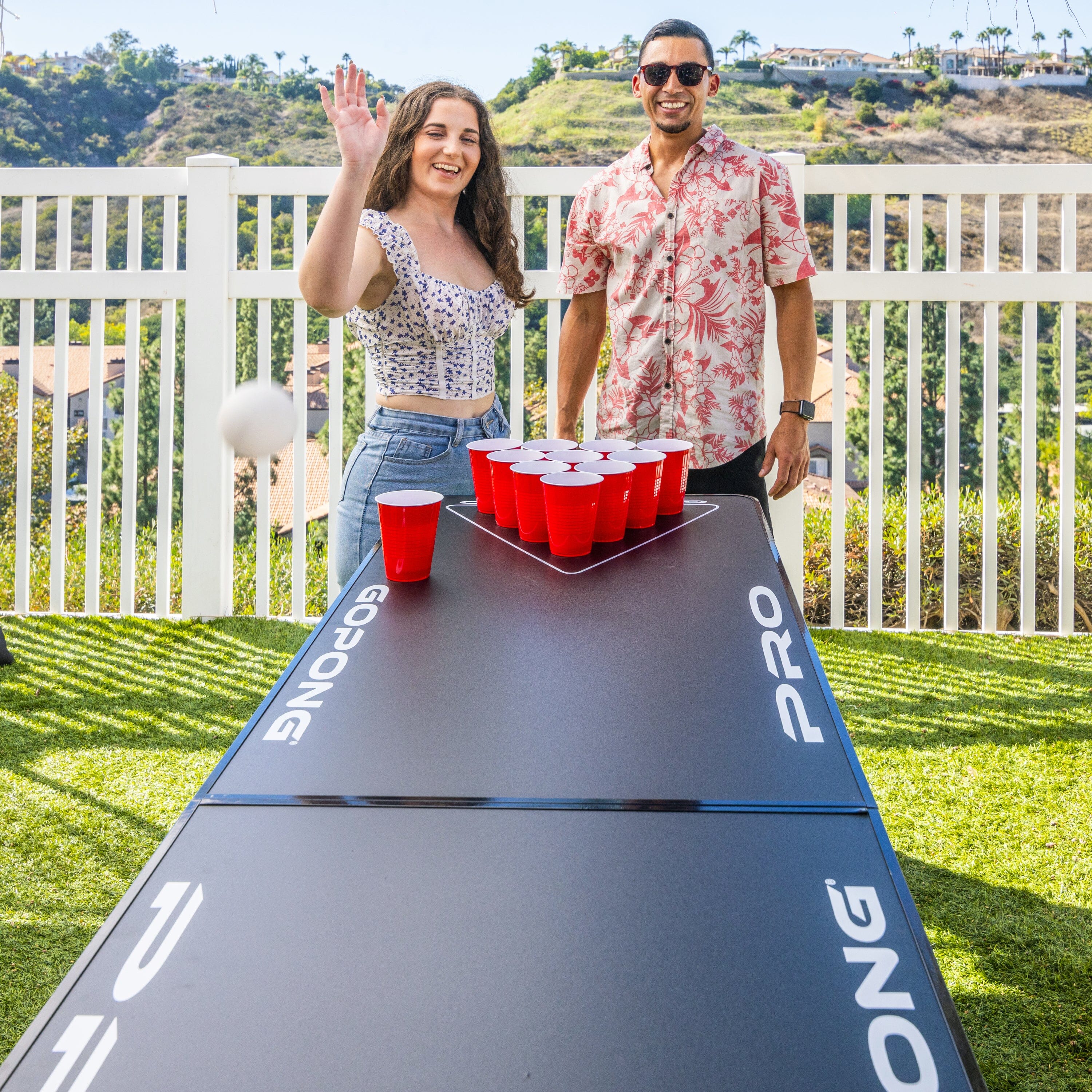 a man and woman standing next to a table with a red cup
