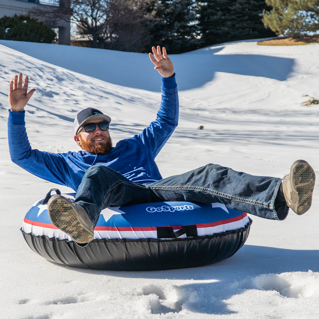 Man enjoying snow tubing on a snowy hill with a GoSports tube.