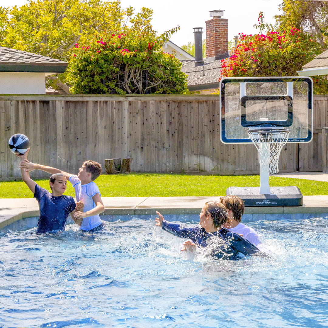 Children playing basketball in a pool with a backyard setting