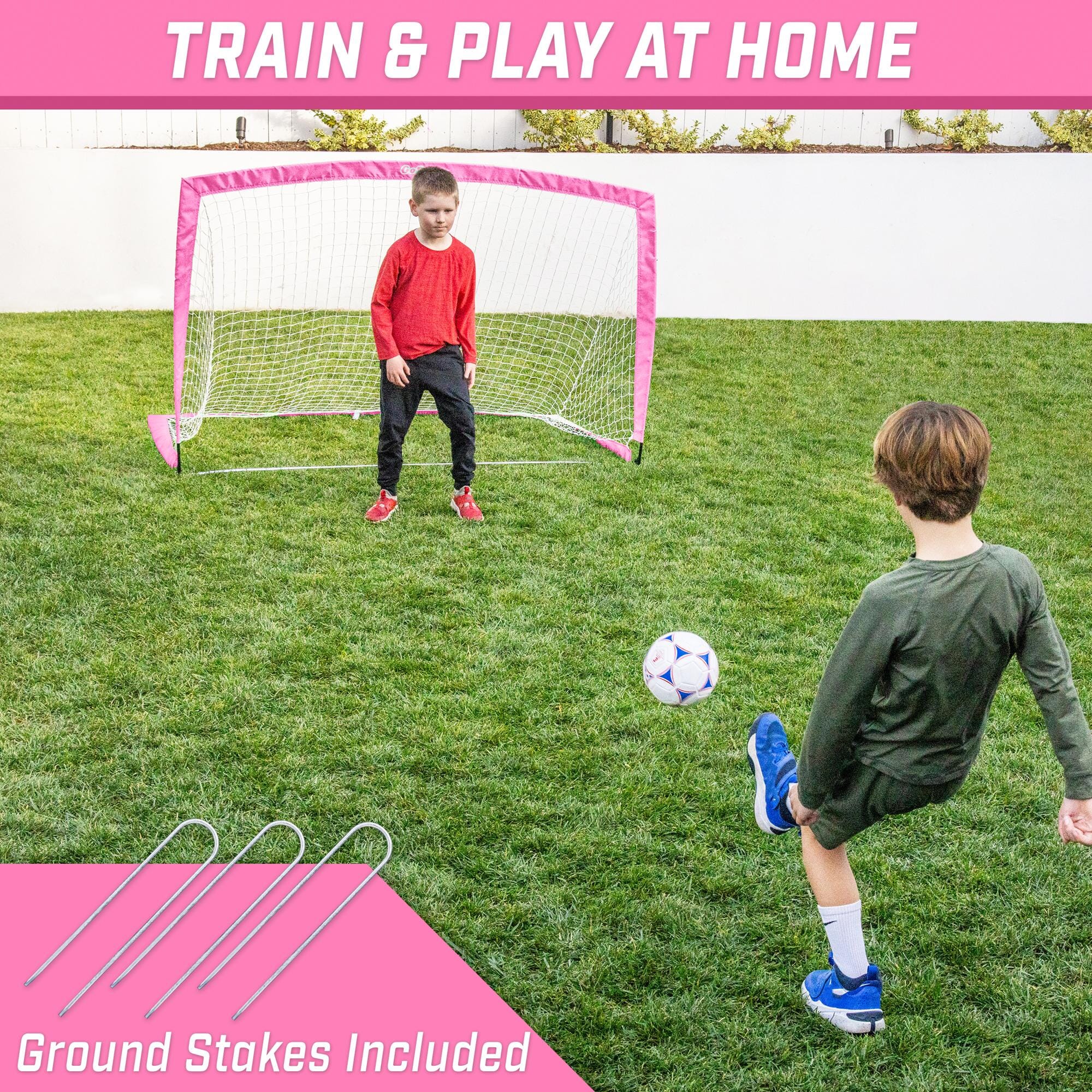 a young boy playing soccer with a pink goal