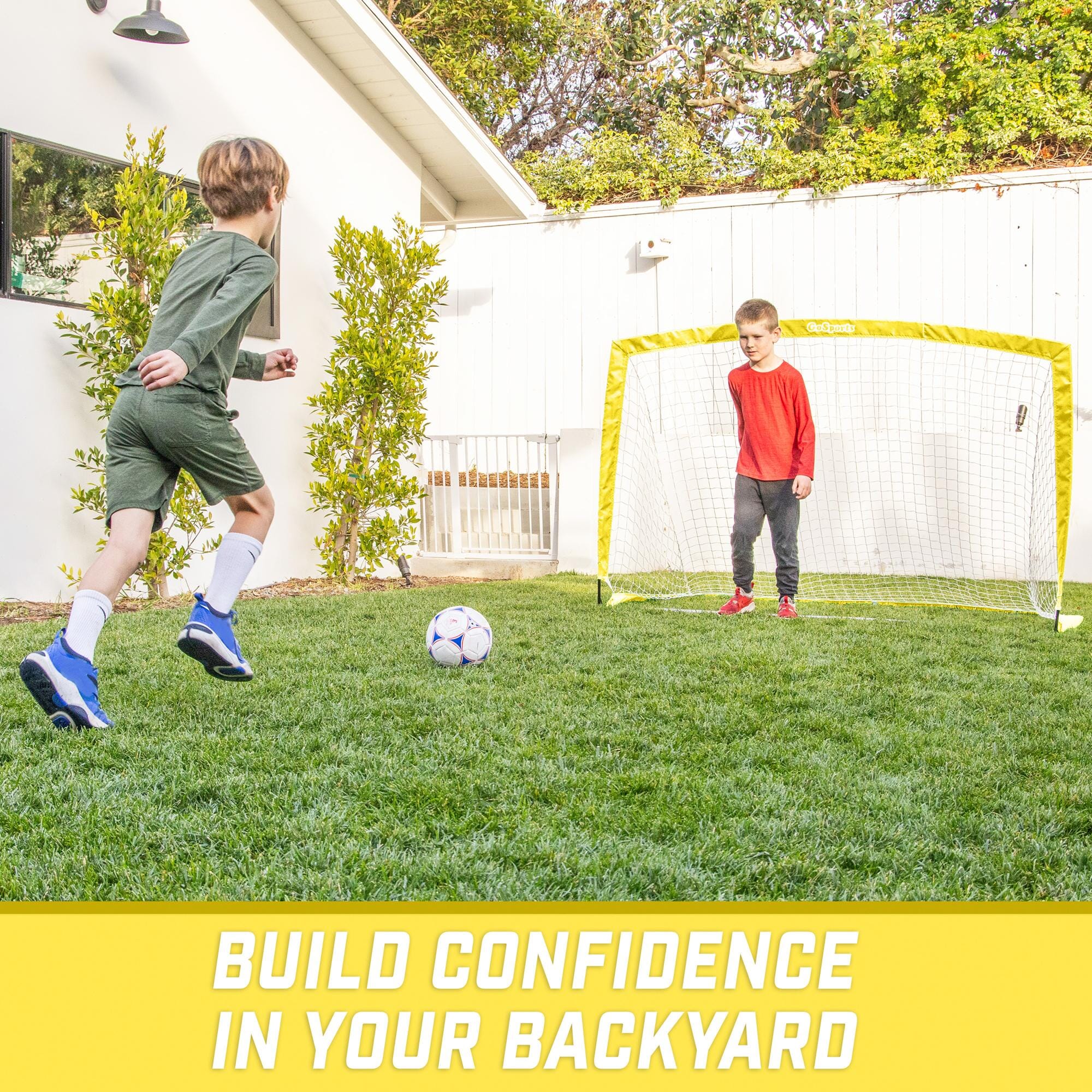 a young boy kicking a soccer ball in the yard