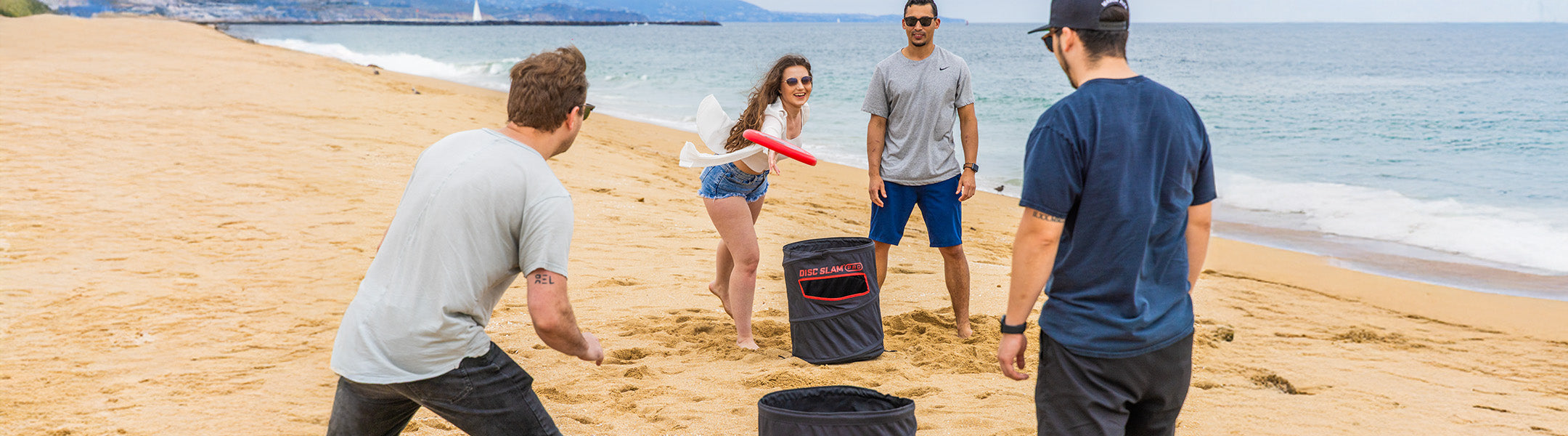 People playing disc slam on a sandy beach with ocean in the background