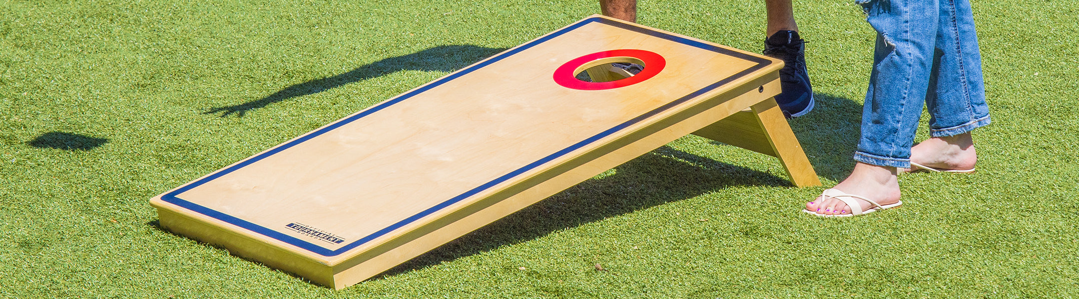 Cornhole board with a red target on a grassy field