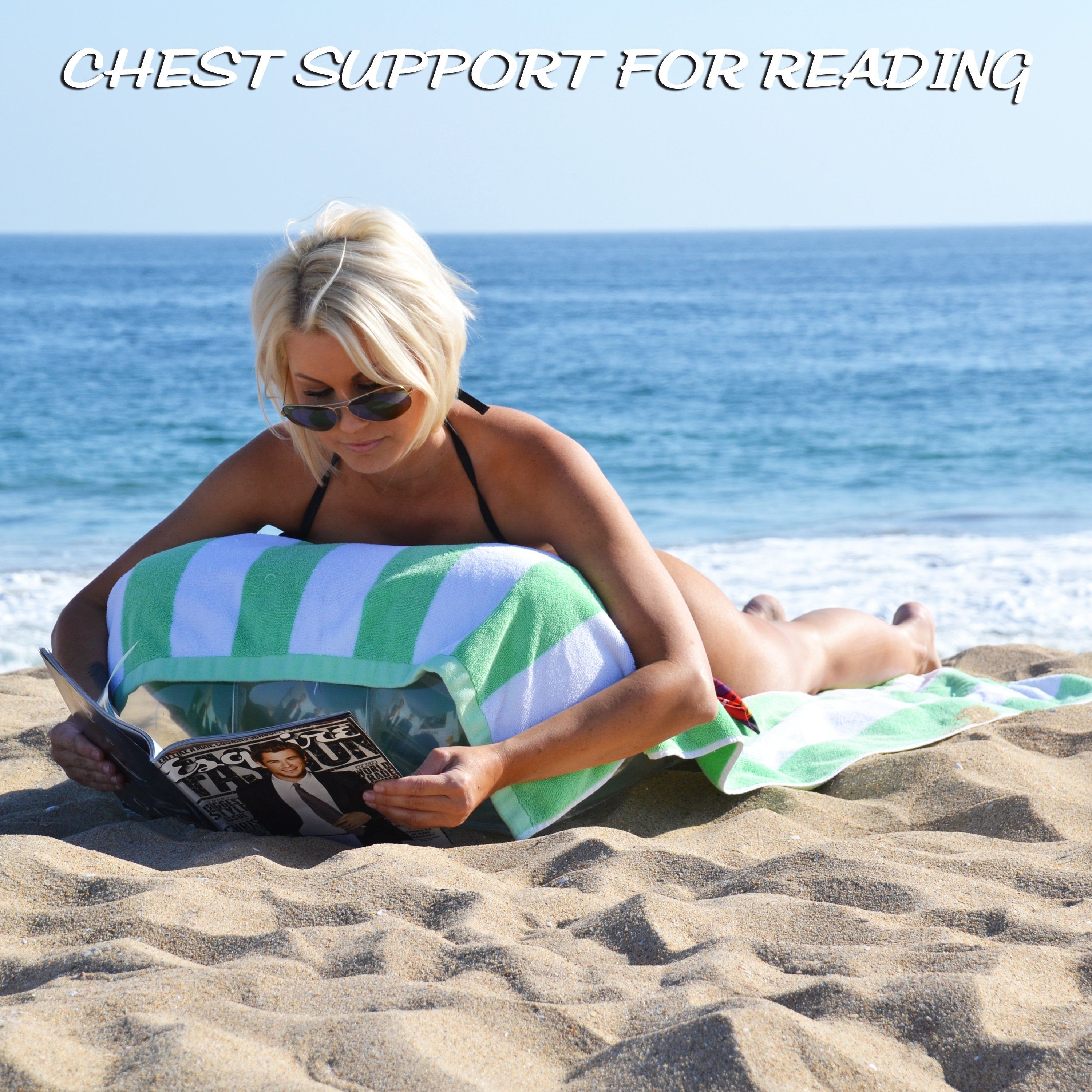 a woman laying on the beach with a book