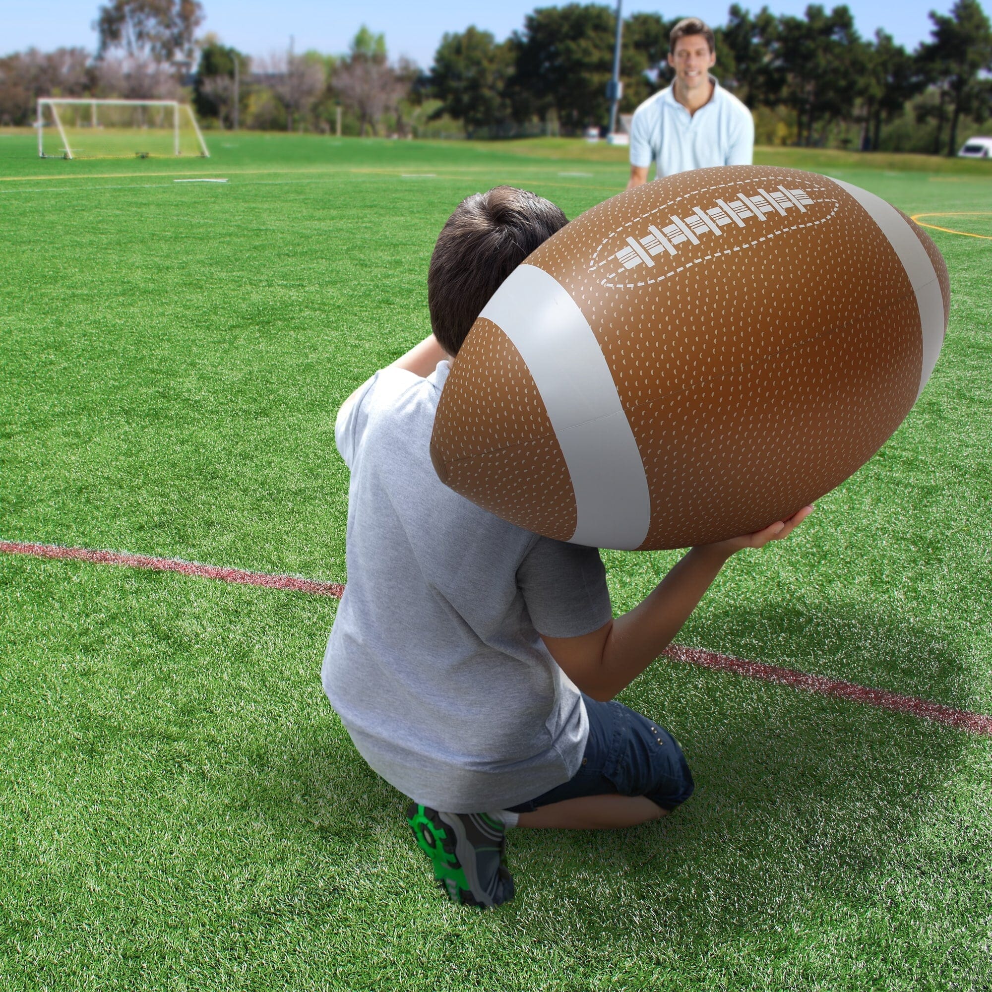 a boy kneeling on the ground with a football