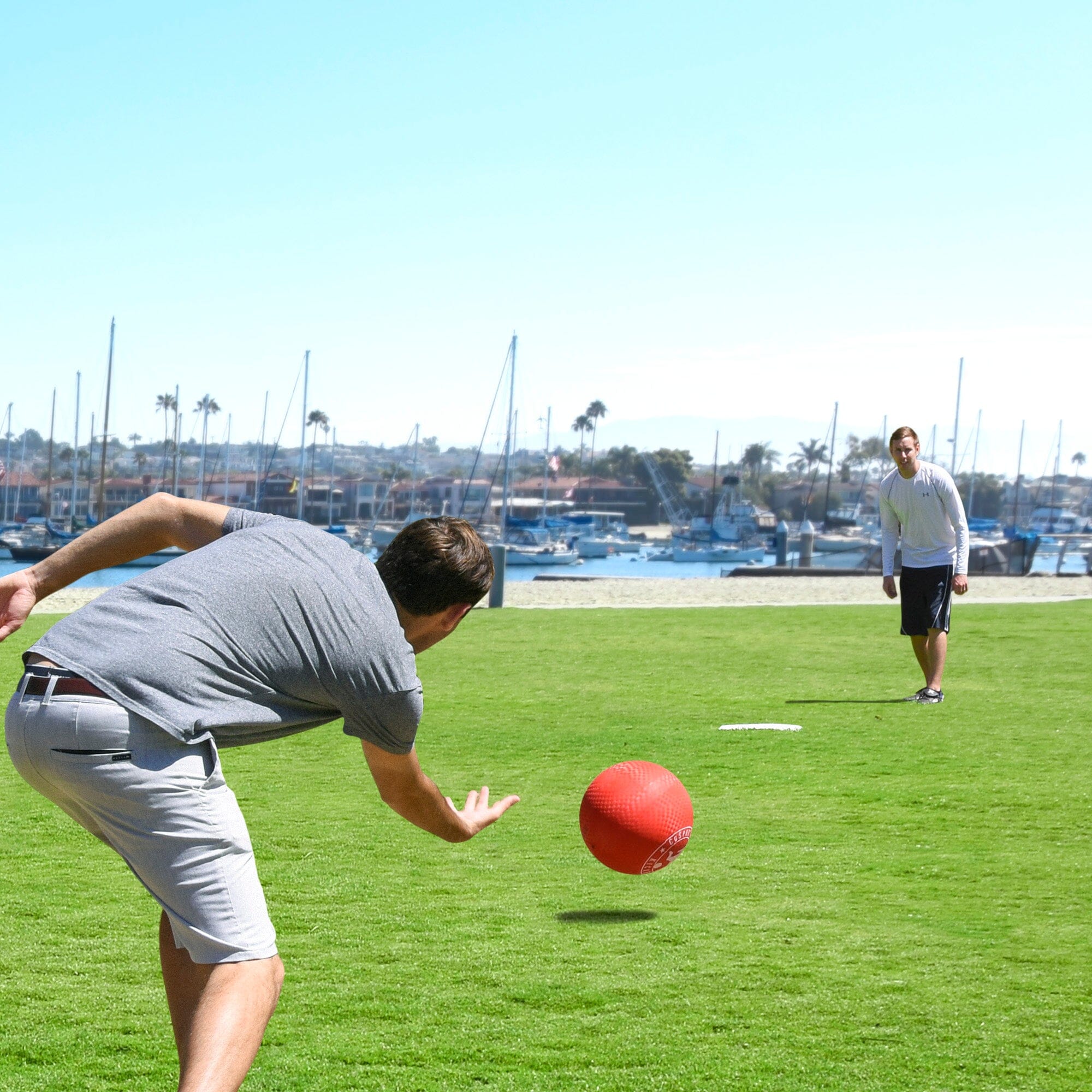 a man in a gray shirt is throwing a red ball