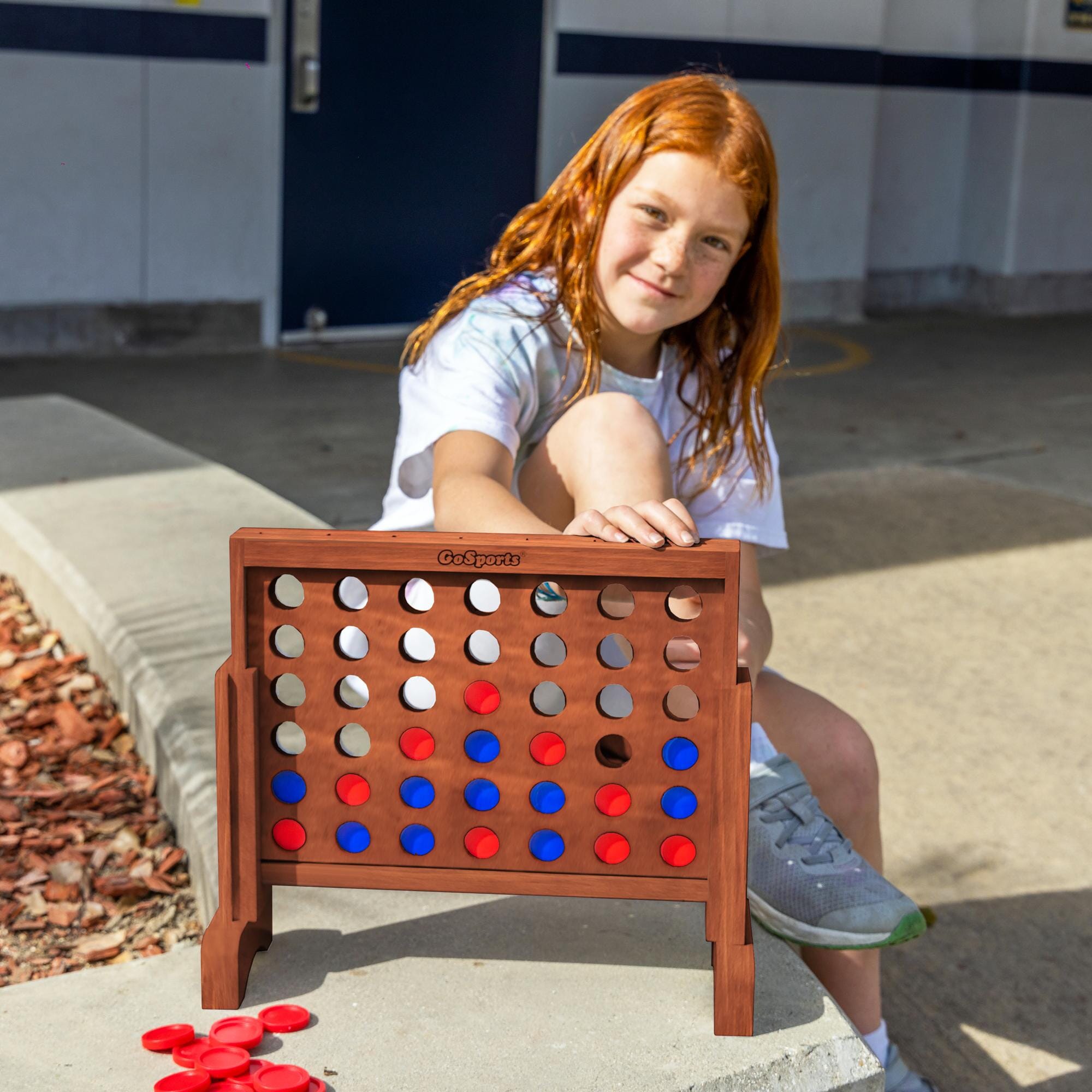 a young girl playing with a giant four in a row game