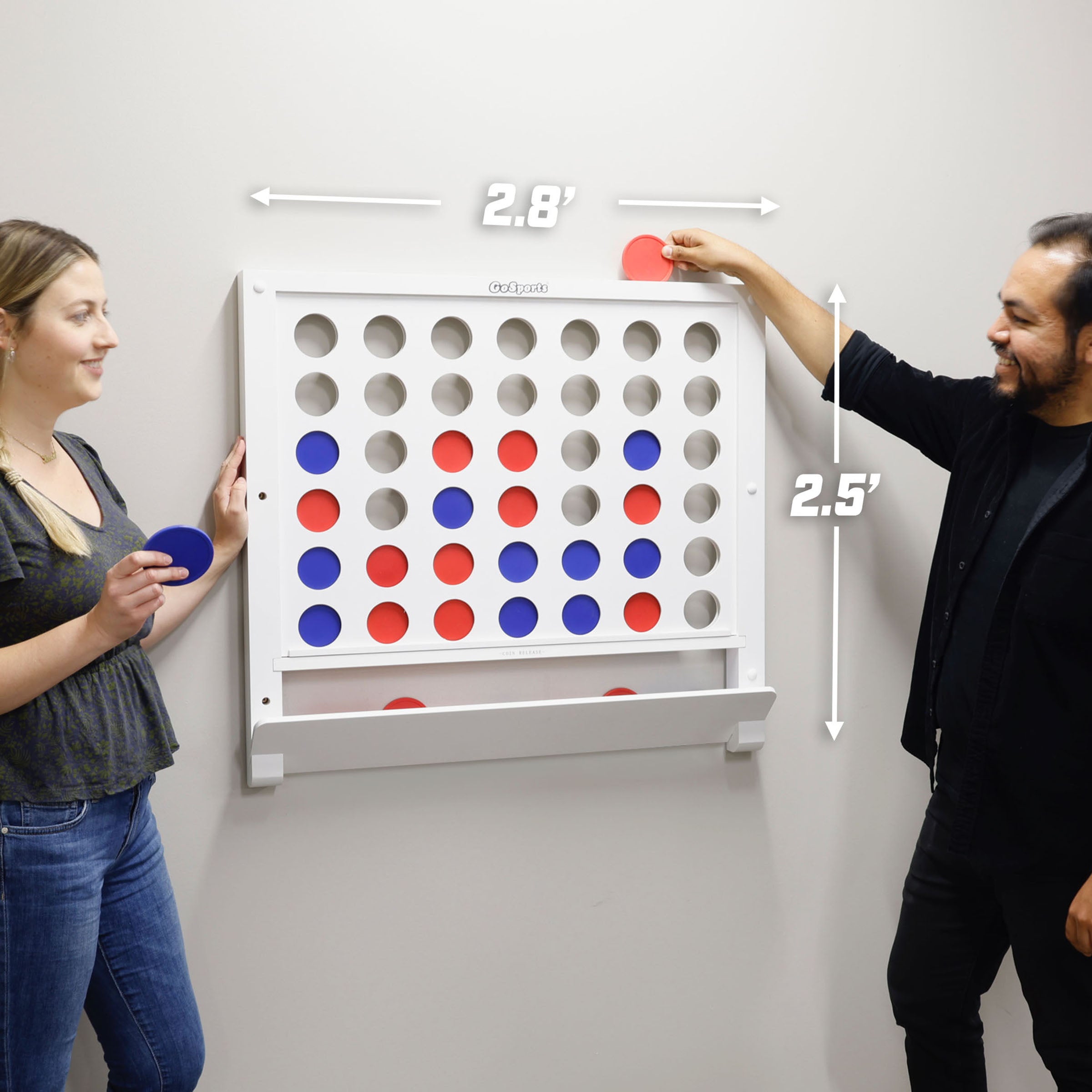 a man and woman standing next to a giant four - sided game