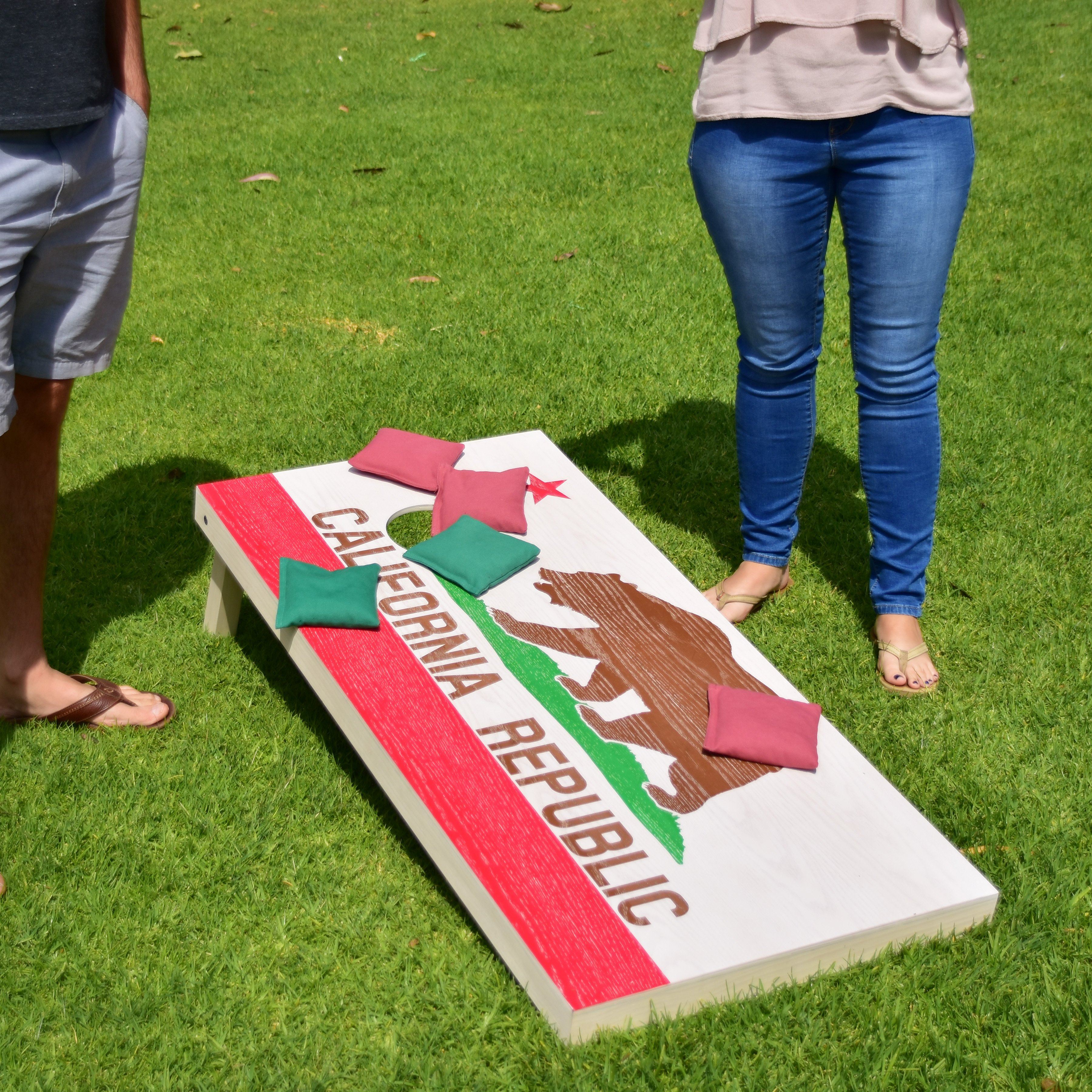 a man and woman standing next to a giant cornhole