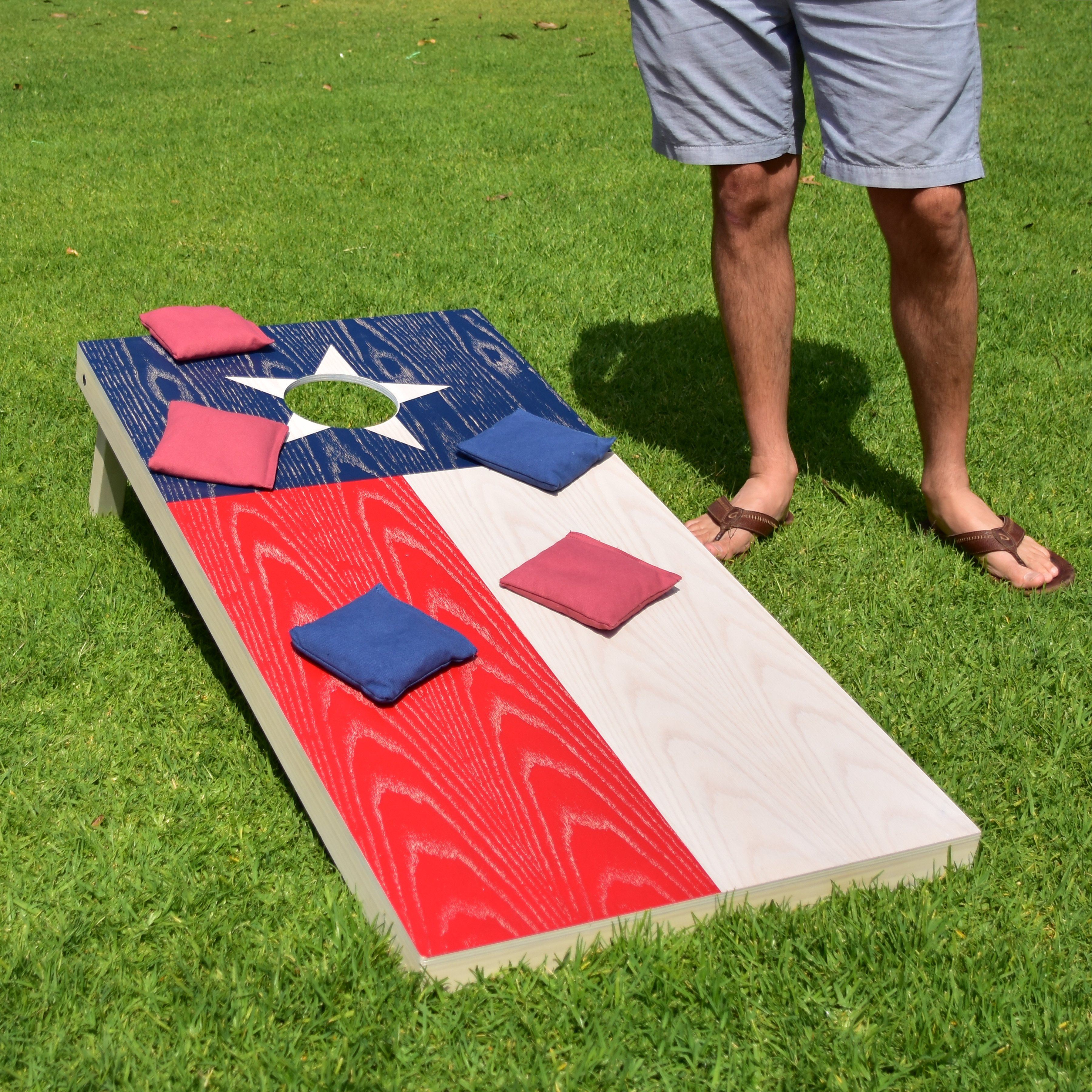 a man standing next to a cornhole on a lawn