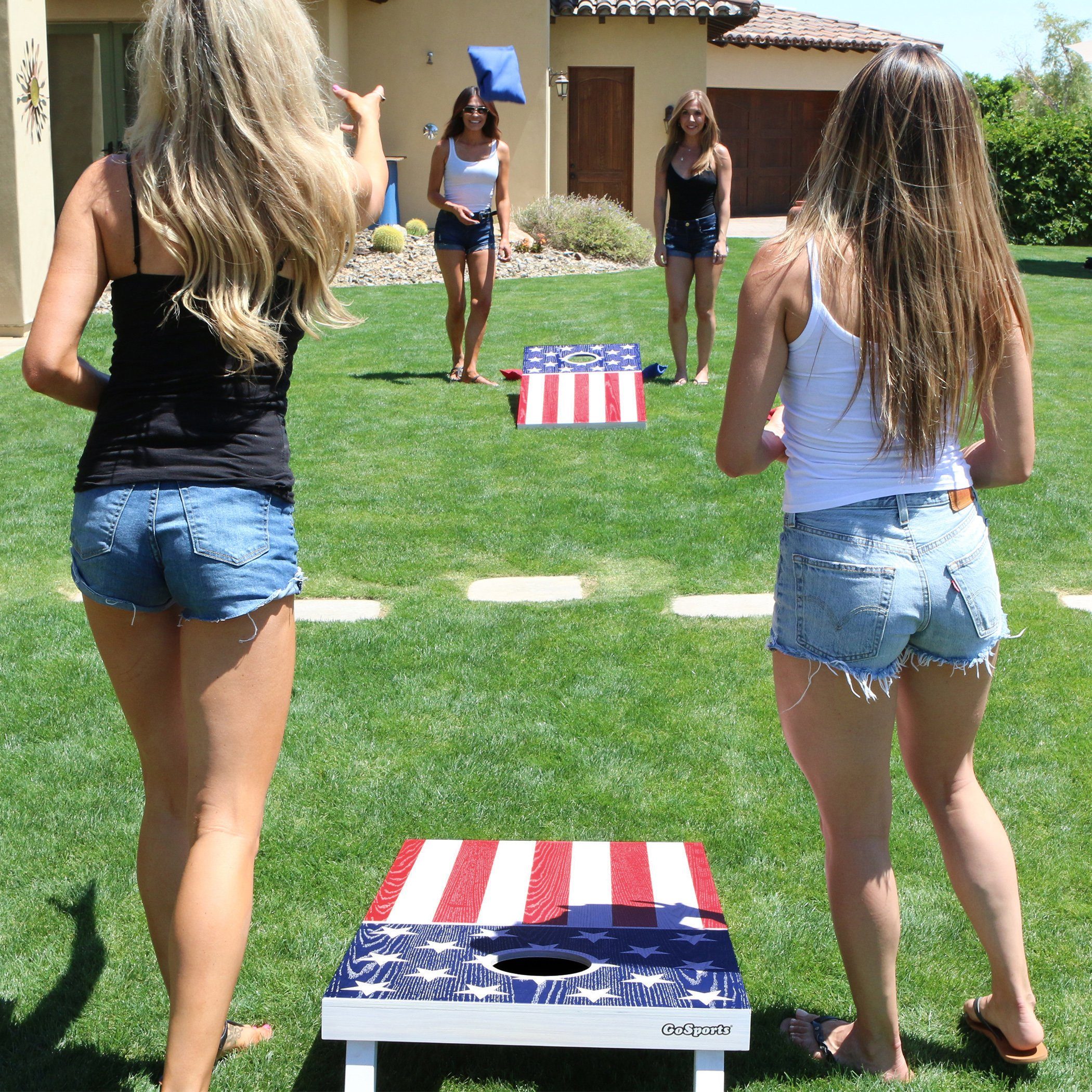 two women playing corno game in the yard