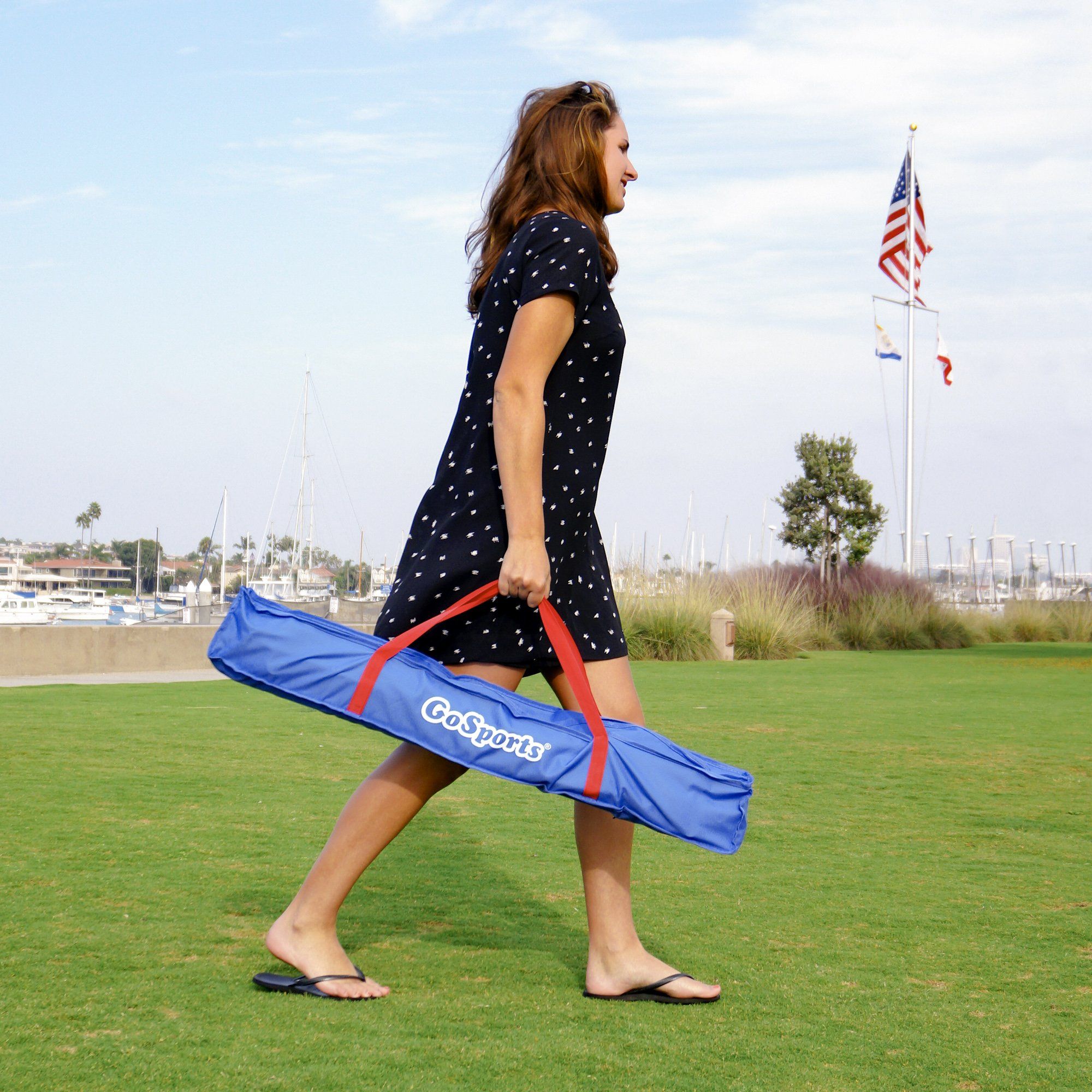 a woman walking across a field carrying a blue bag