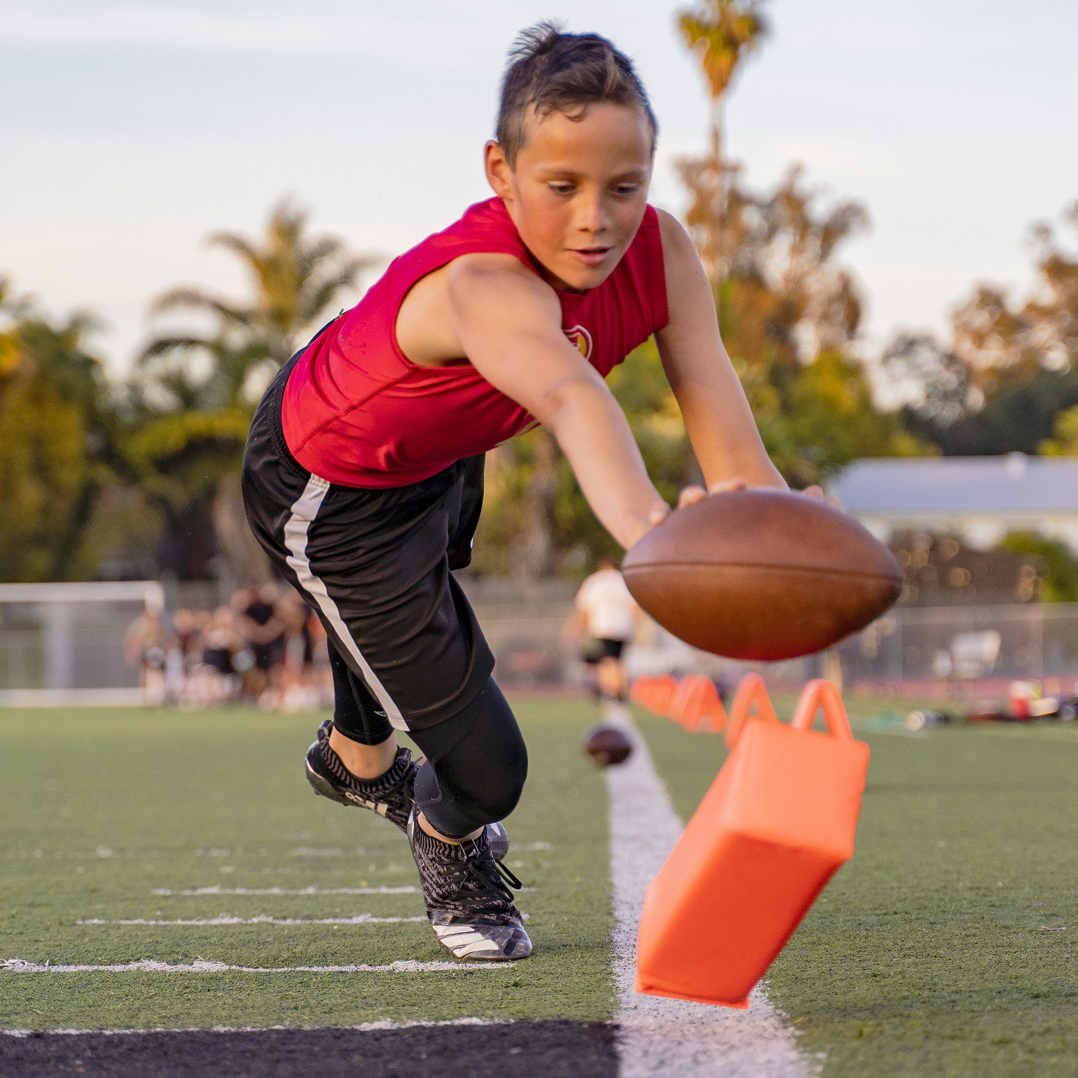 a young boy in a red shirt is catching a football
