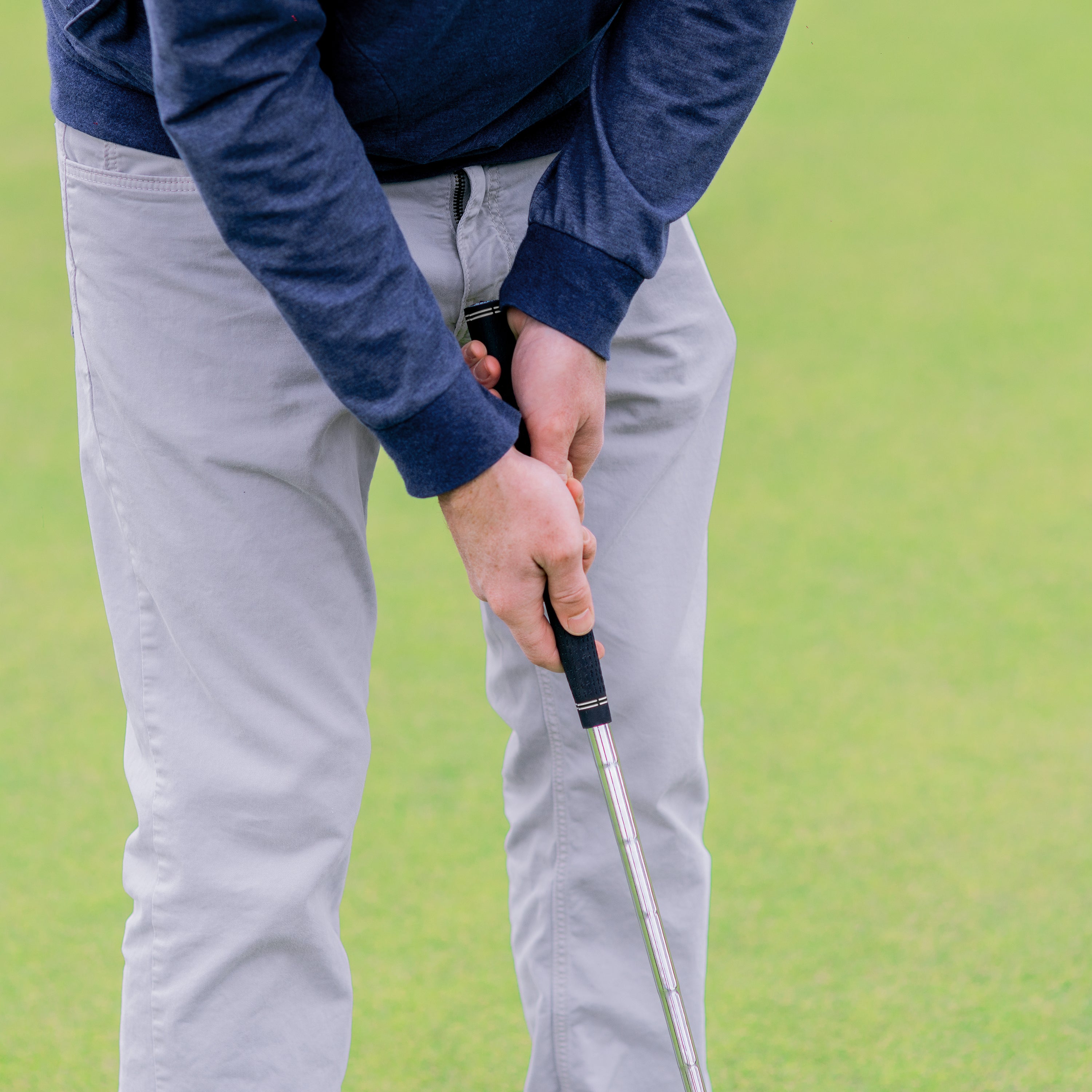 a man holding a golf club and putting it