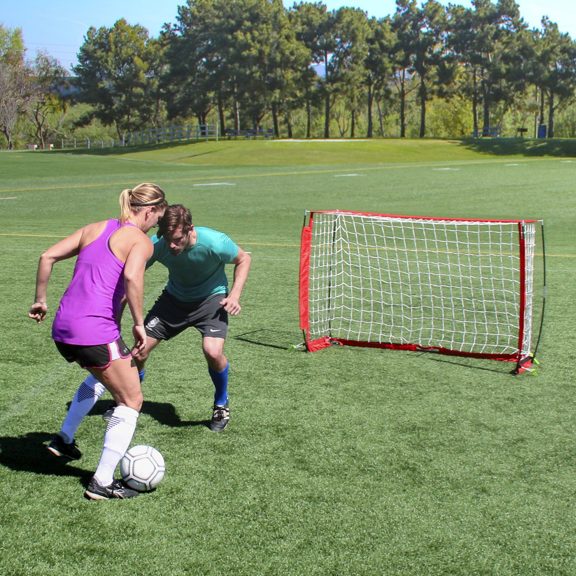 a woman in a purple shirt and blue shorts is playing soccer