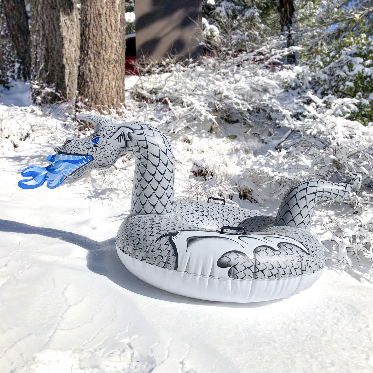 Gray GoSports Ice Dragon snow tube with scaled neck, blue frost-fire breath & black handle on snow by pine trees