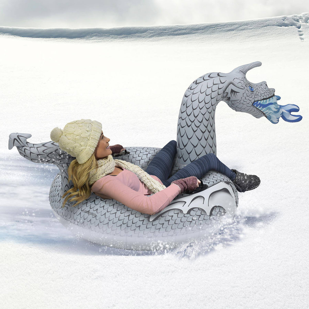 Woman sledding down a snowy slope in a gray GoSports Ice Dragon snow tube with blue frost-fire breath
