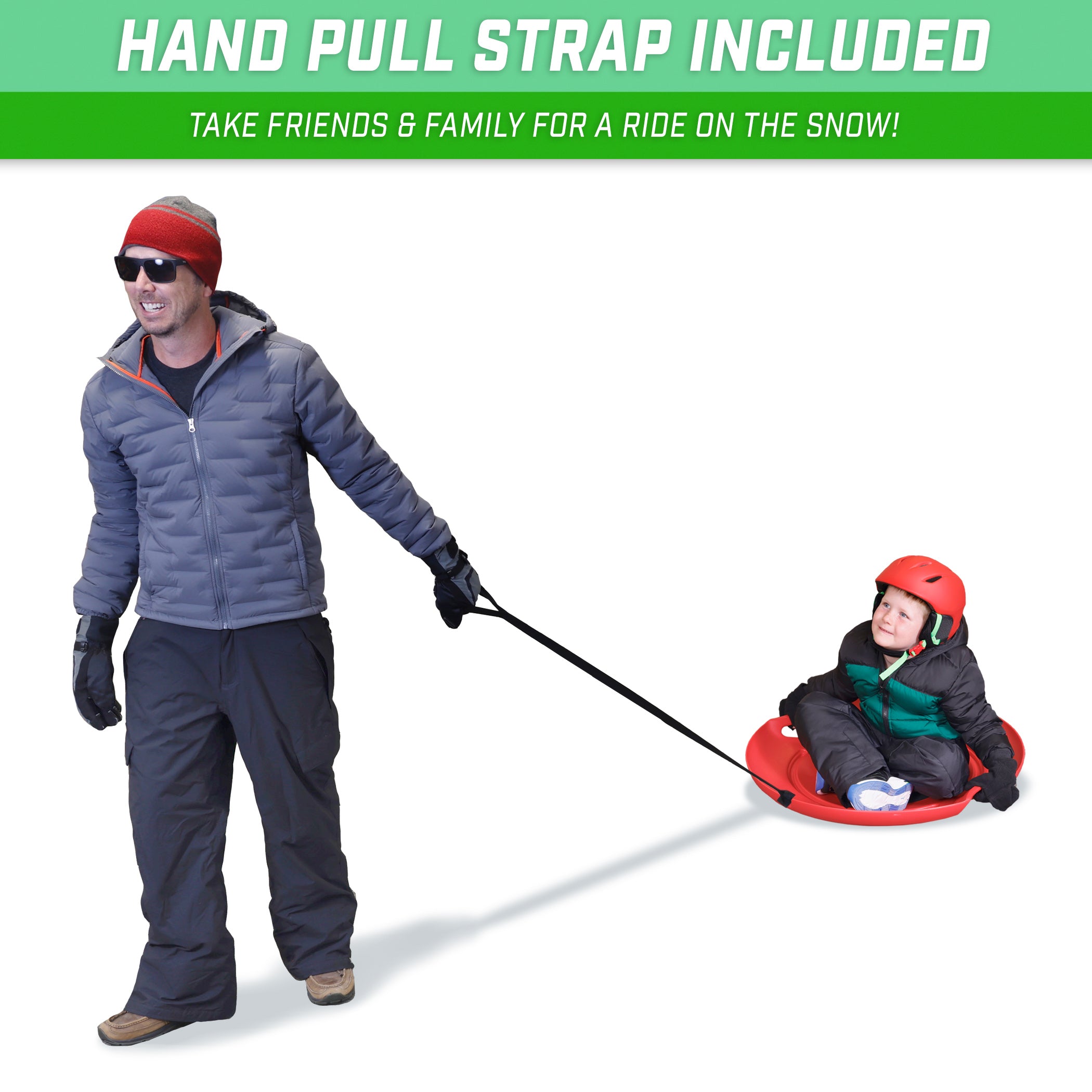 man pulling from a long handle a child with snow gear red helmet on top of a red saucer