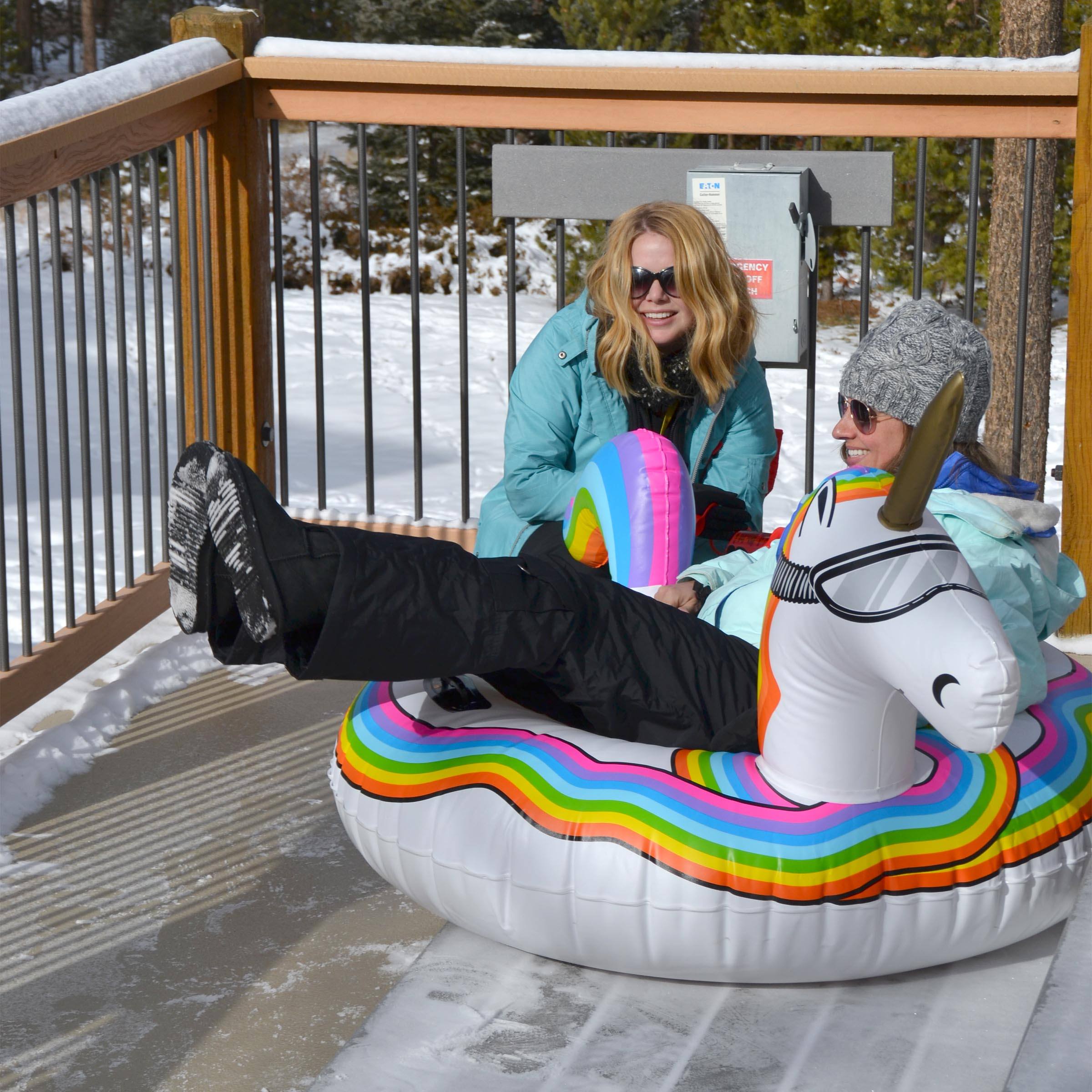 a woman sitting on a rainbow colored inflatable