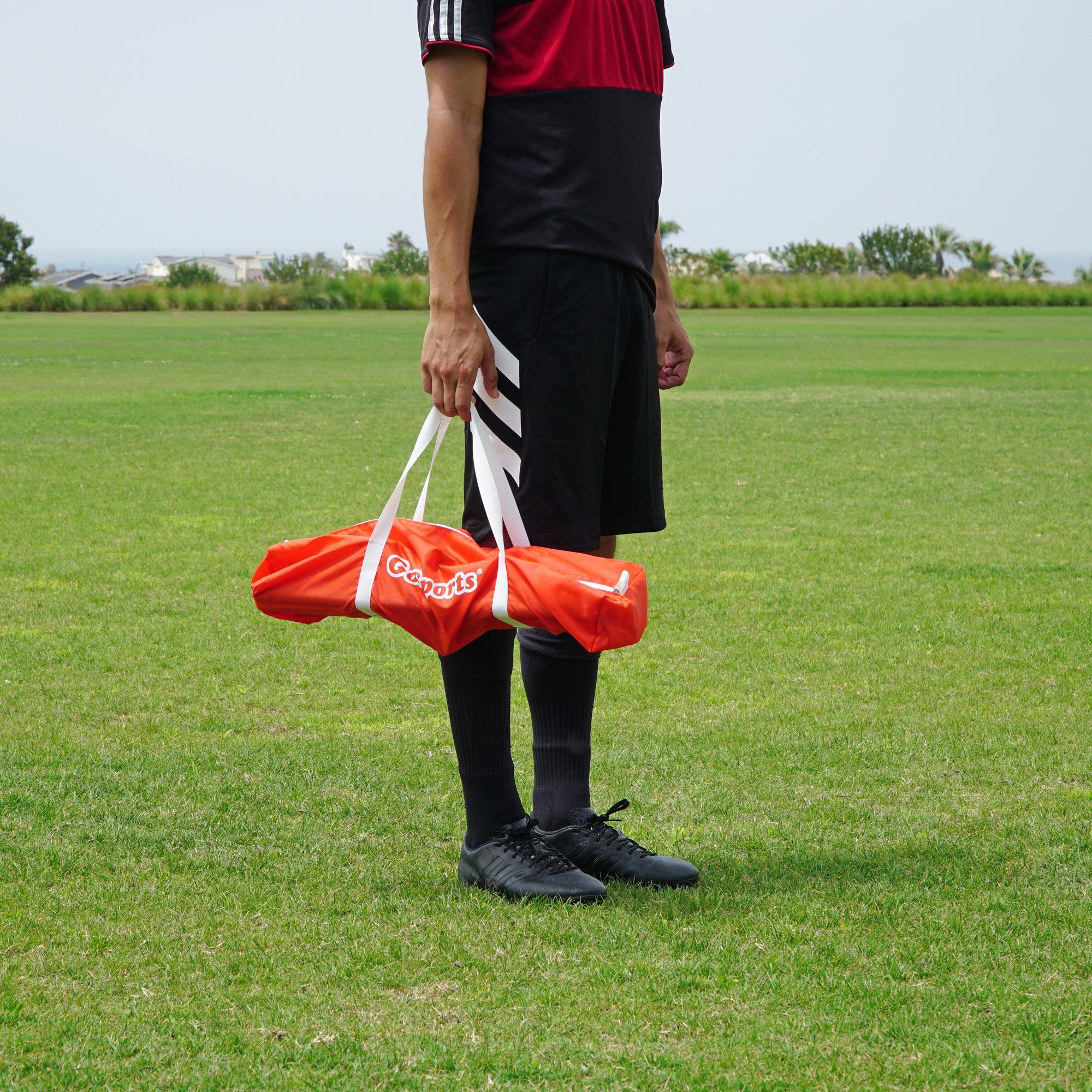 a man in a red shirt and black shorts holding a red bag