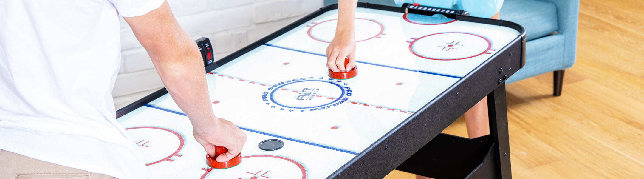 Air hockey table game in progress with players using paddles.