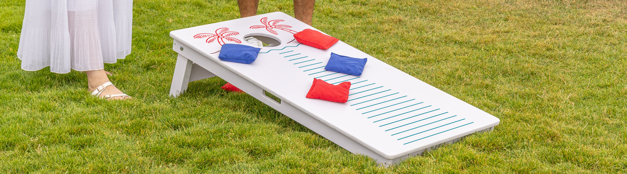 Cornhole game set on grass with players in the background