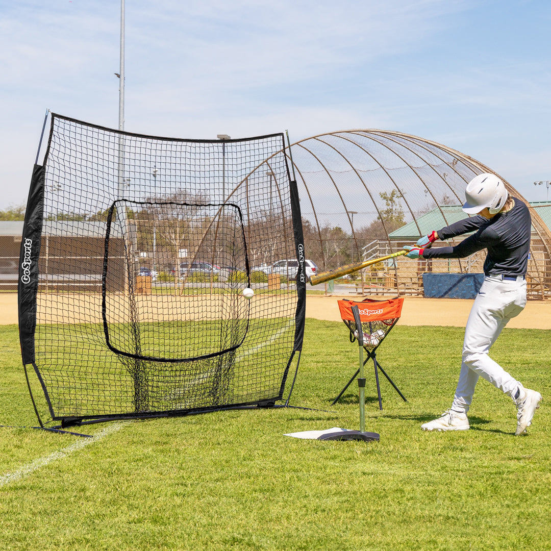 Person practicing batting in a baseball cage on a sunny day