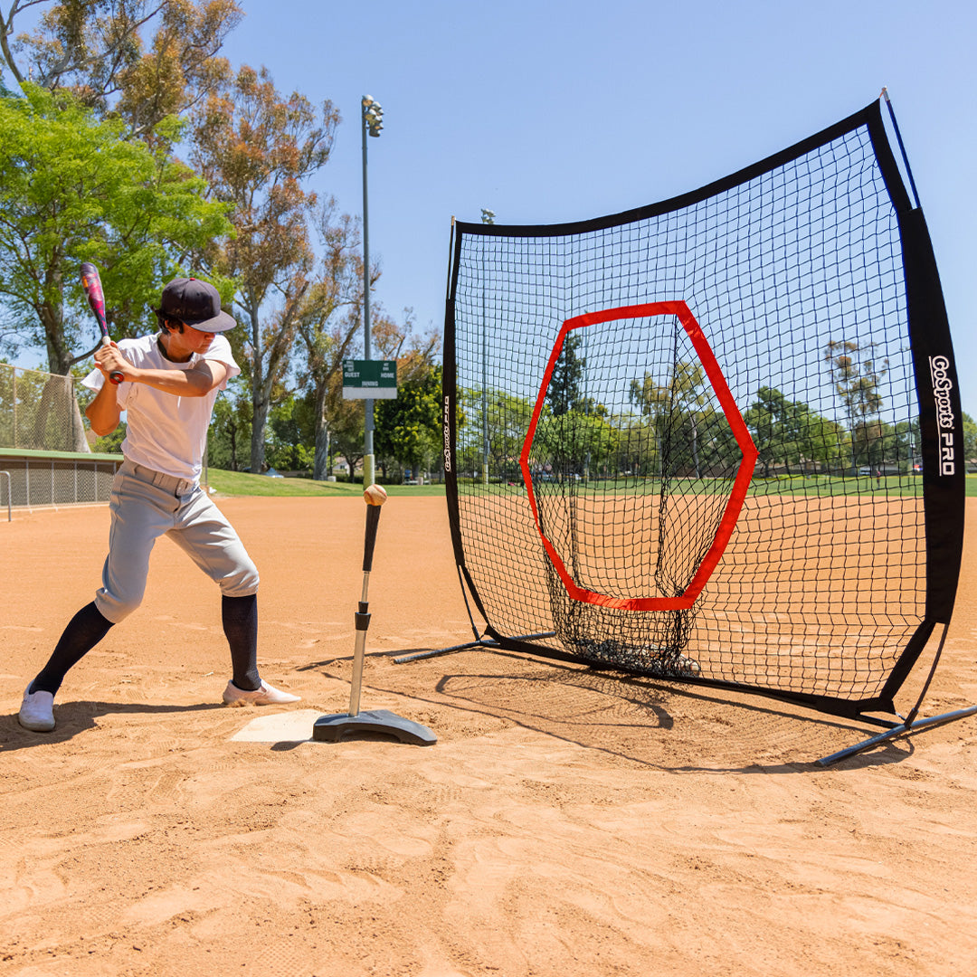 Person practicing batting with a baseball net on a baseball field