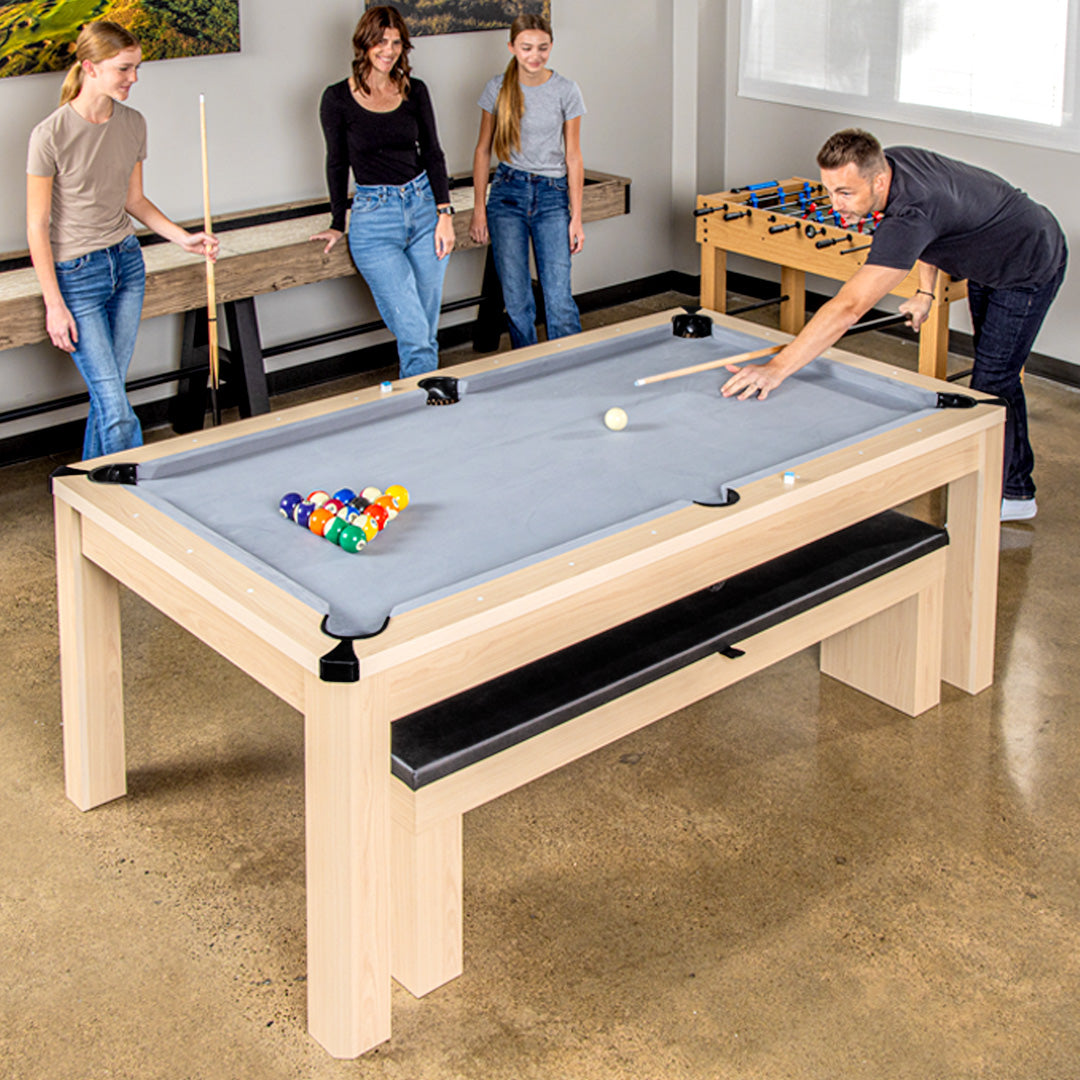 People playing pool in a room with a pool table and foosball table.