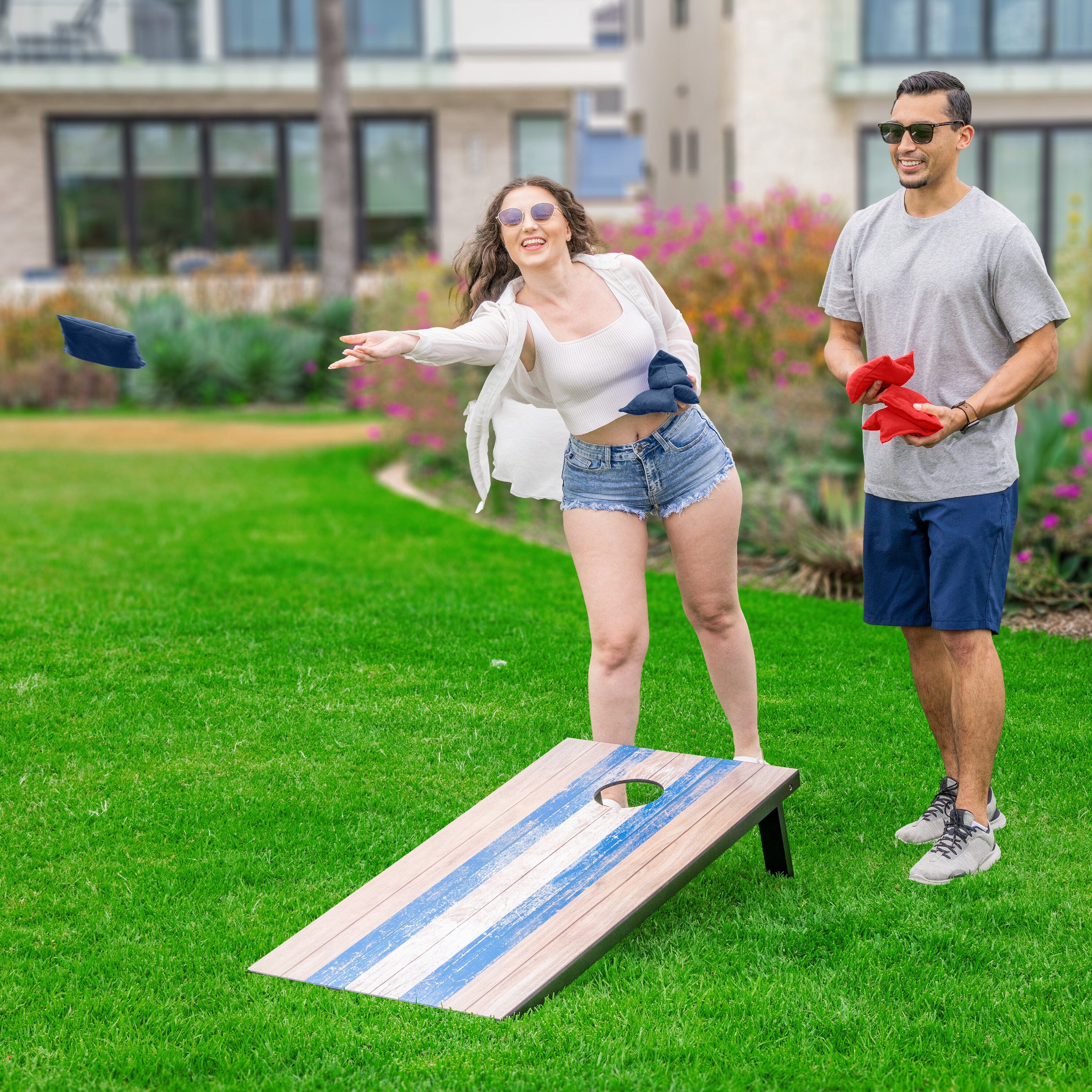 a man and woman playing cornhole game in the yard