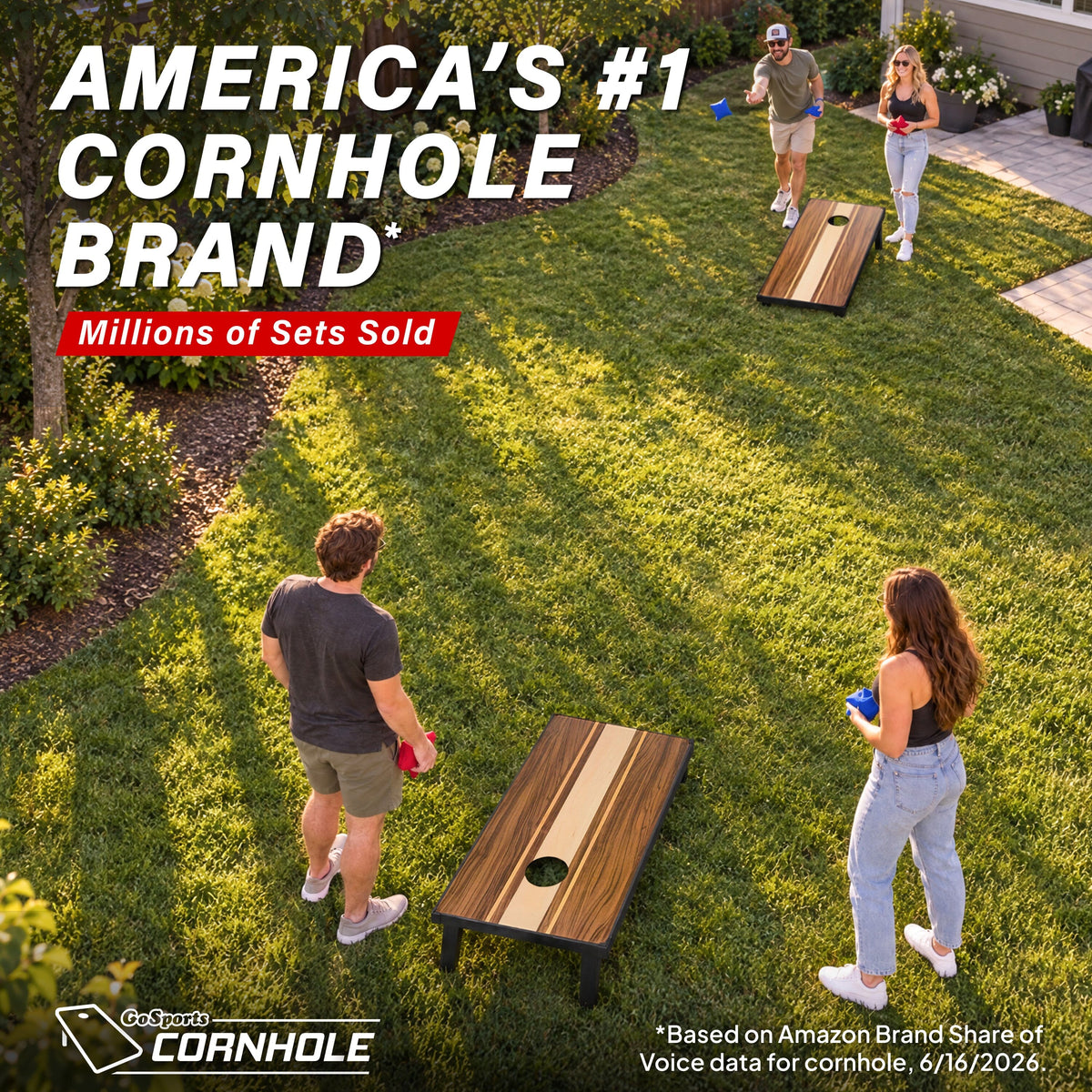 Aerial view of friends playing a GoSports walnut 4x2 ft portable cornhole set across a sunny backyard lawn