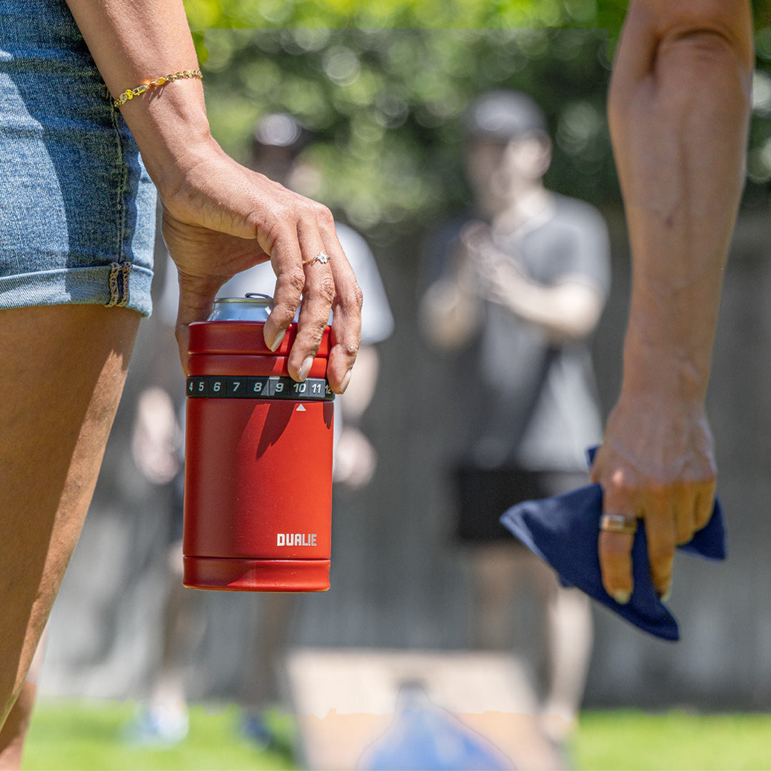 Person holding a red cup labeled 'DUALIE' with blurred people in the background