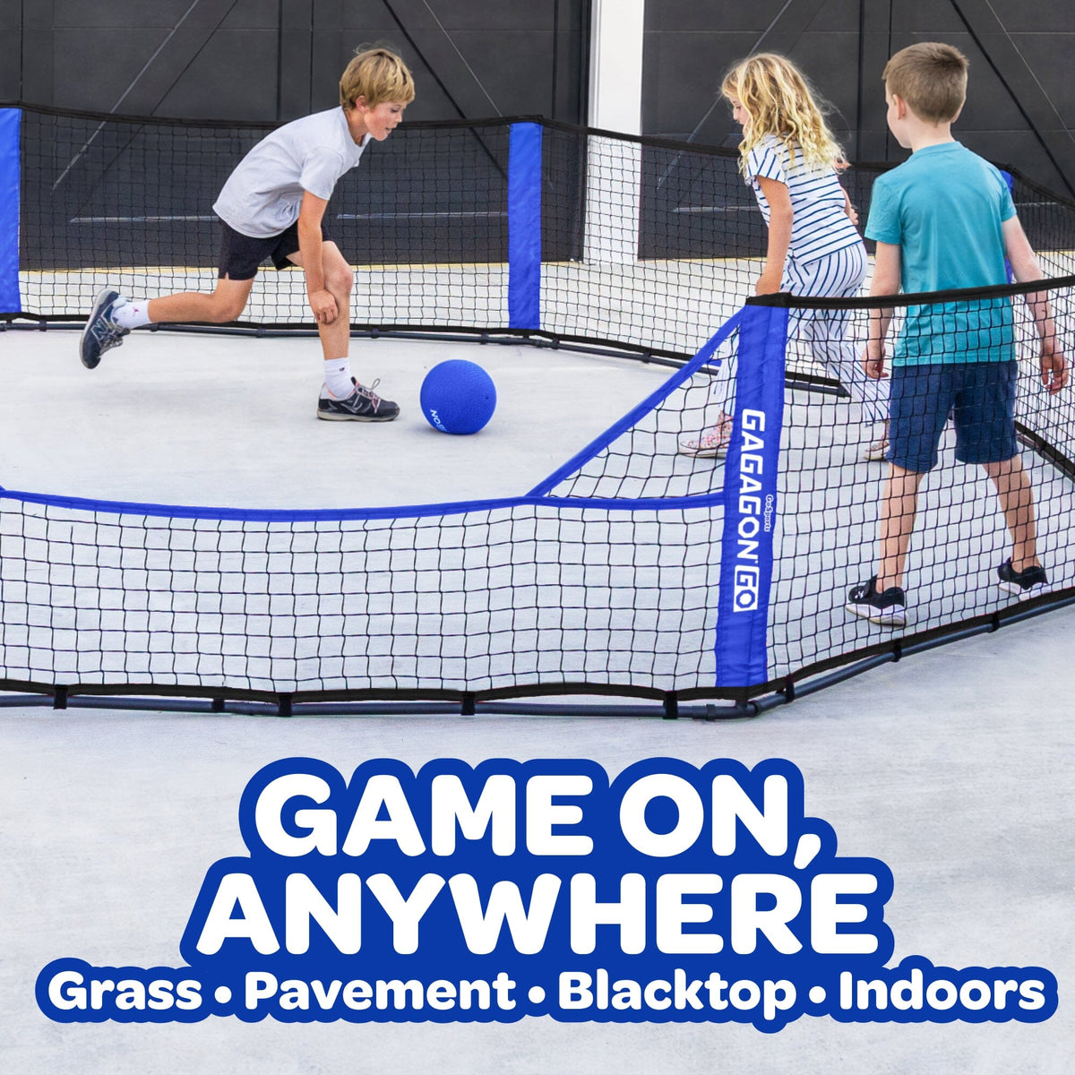 Three children playing with a blue ball inside a black and blue enclosed net game court on a smooth indoor surface. Large text at the bottom reads 'GAME ON, ANYWHERE' with 'Grass • Pavement • Blacktop • Indoors' below.