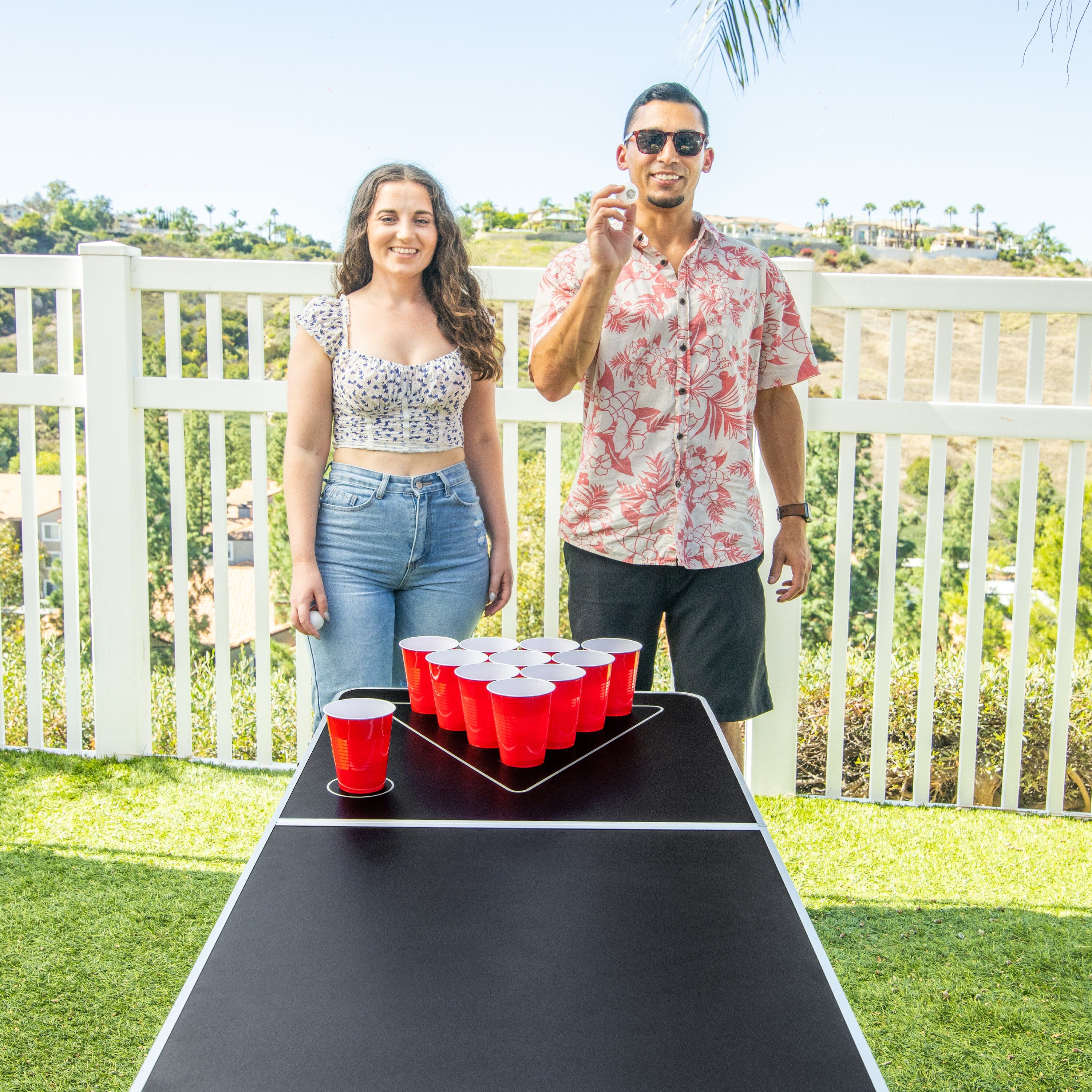 a man and woman standing next to a table with a red cup