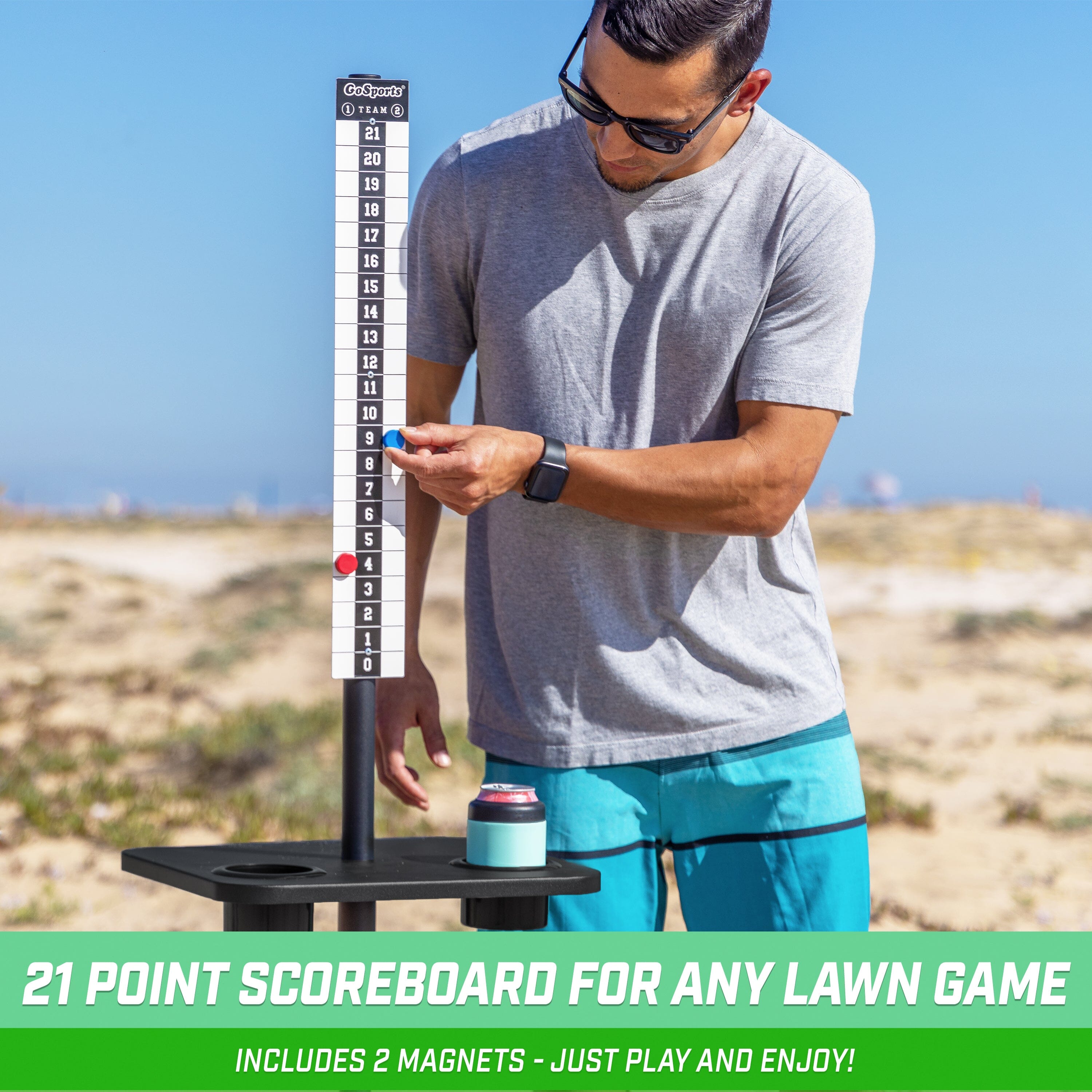 a man standing on the beach holding a large ruler