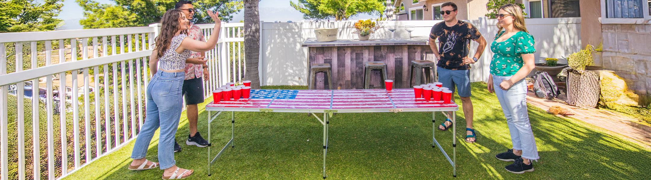 People playing a game of beer pong on a backyard deck.