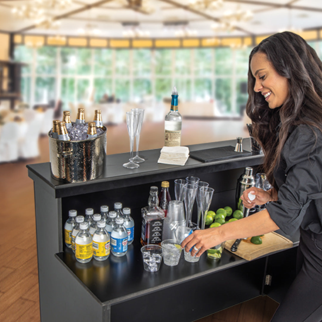 Woman preparing drinks at a bar with various bottles and glasses.