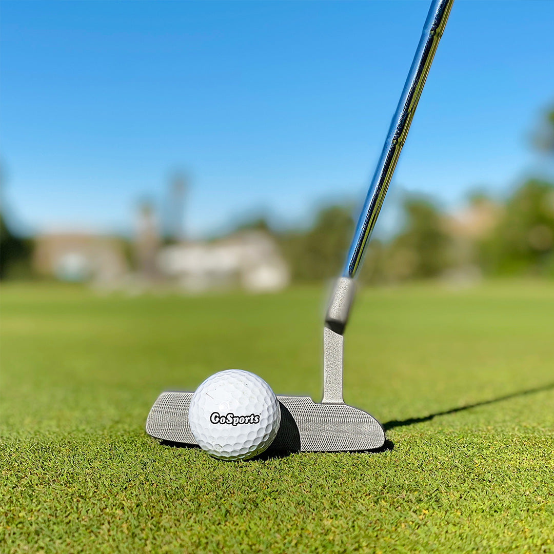 Golf putter and ball on a green with a blurred background