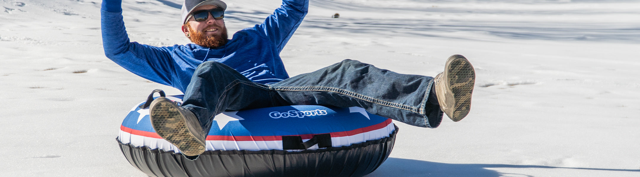 Person sitting on a snow tube with a visible brand logo on a snowy surface