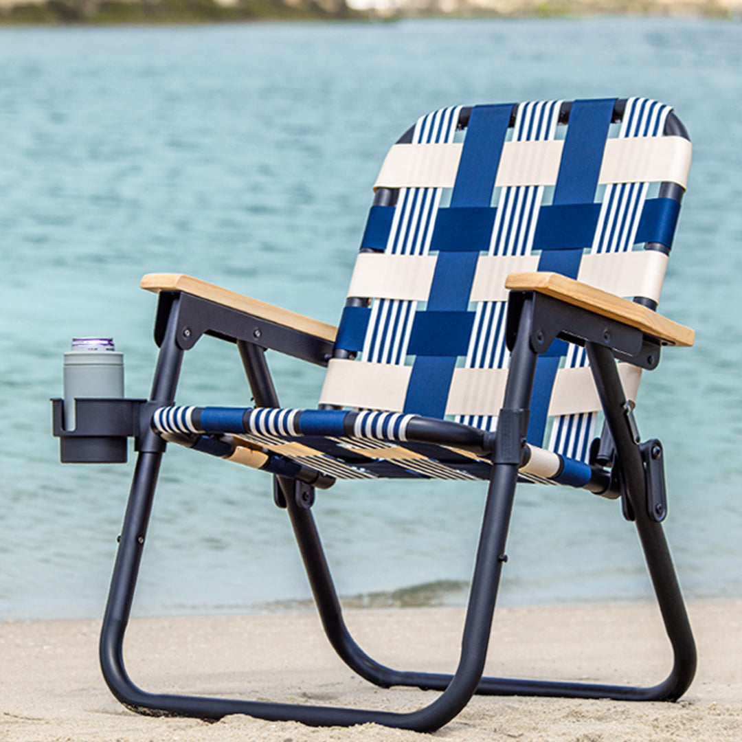 Foldable chair with blue and white patterned seat against a water background