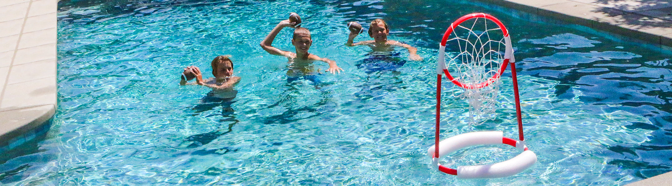 Children throwing a football in a pool with a hoop