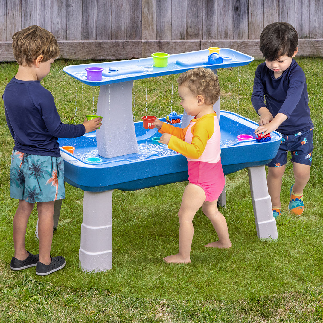 Children playing with a water table in a backyard
