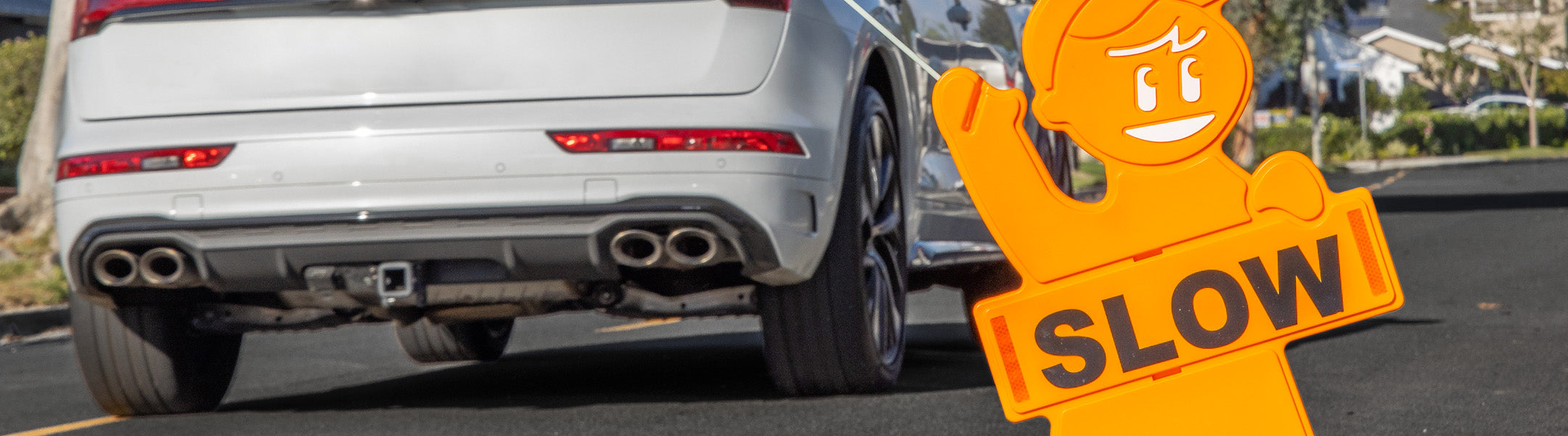 Car driving on a road with a an orange man 'Slow' sign in the foreground