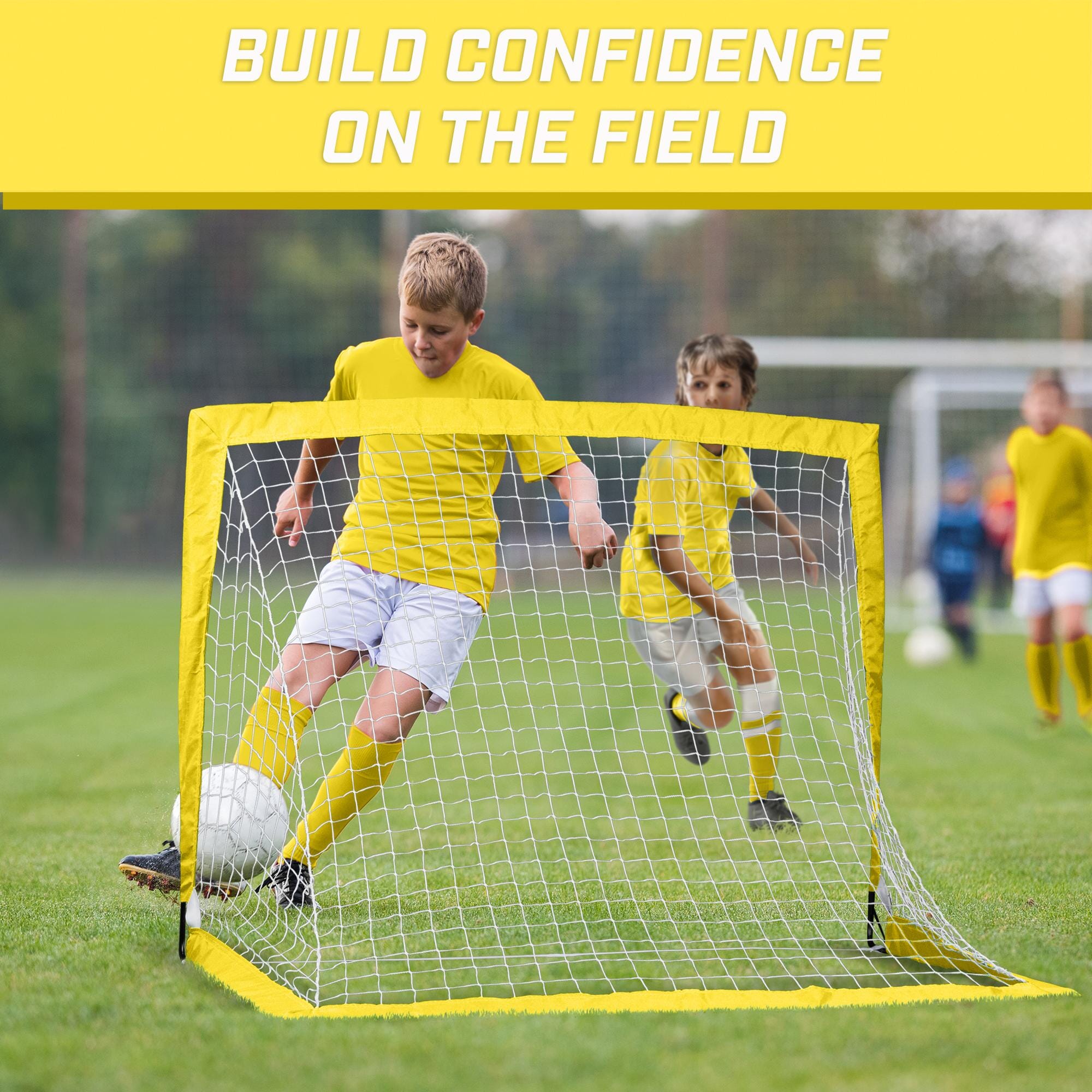 a young boy kicking a soccer ball in a goal net