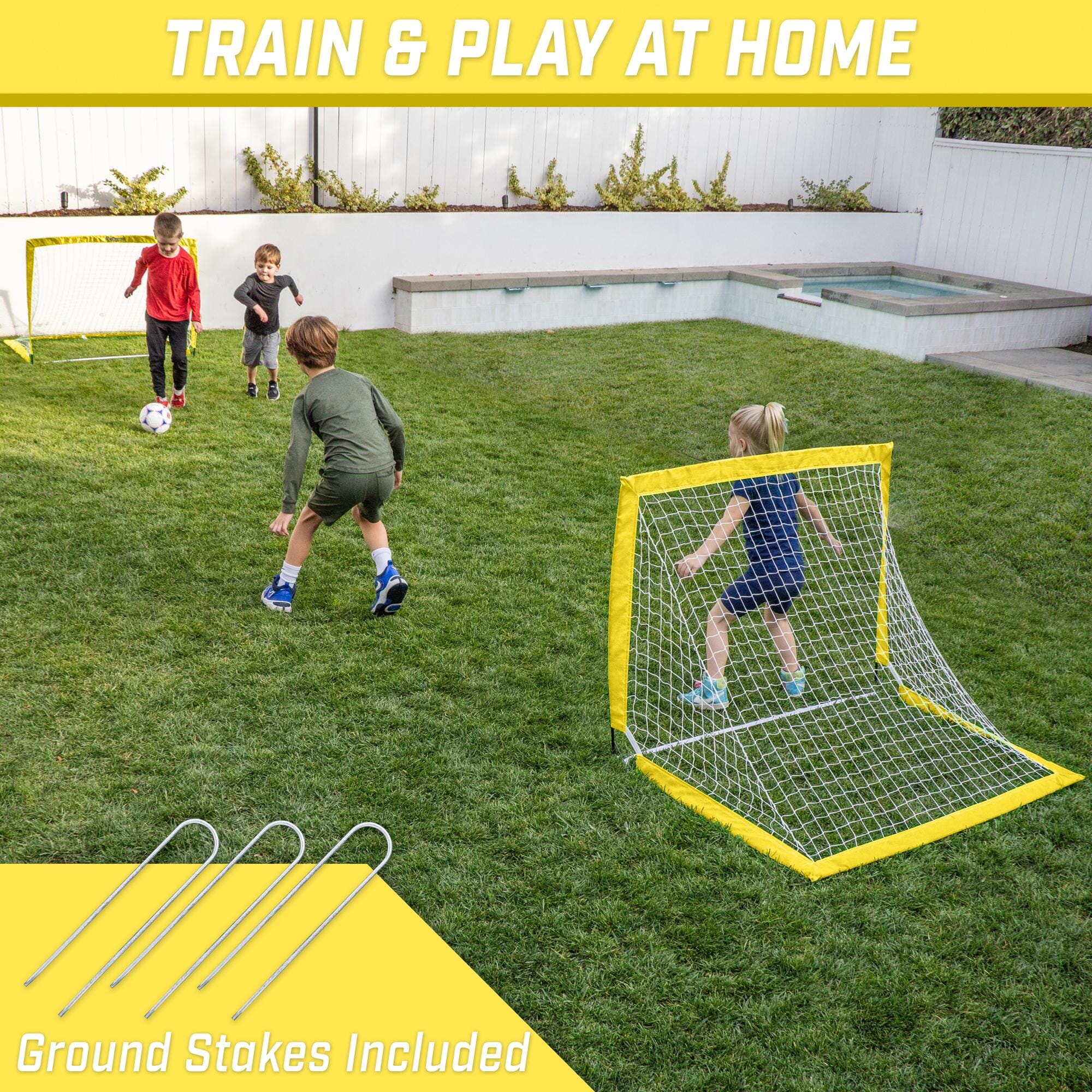 a kid playing soccer in the backyard with a yellow goal